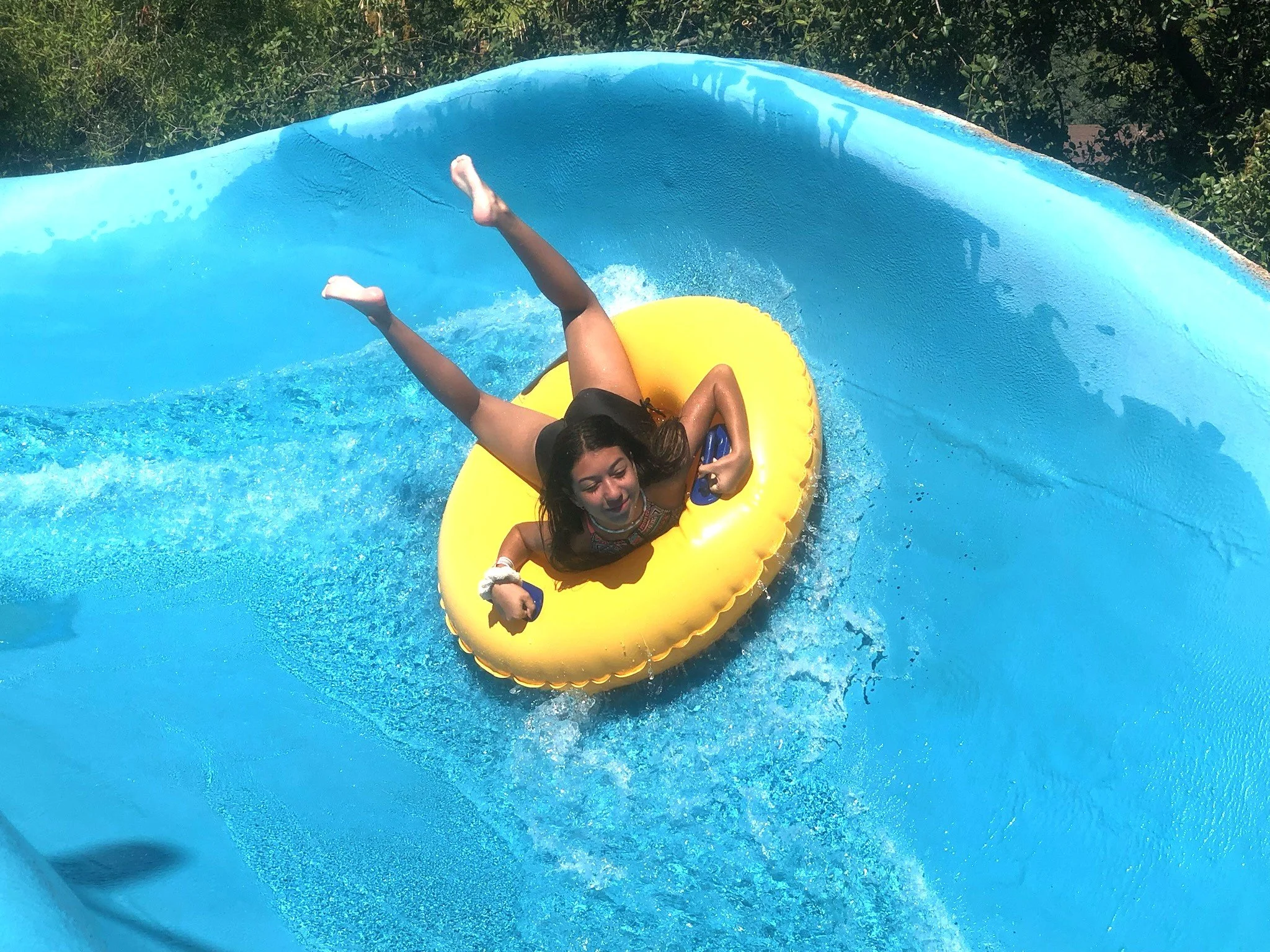 This image shows a girl riding down the Raging River on a single person tube. She is stomach down and forward facing on the ride.