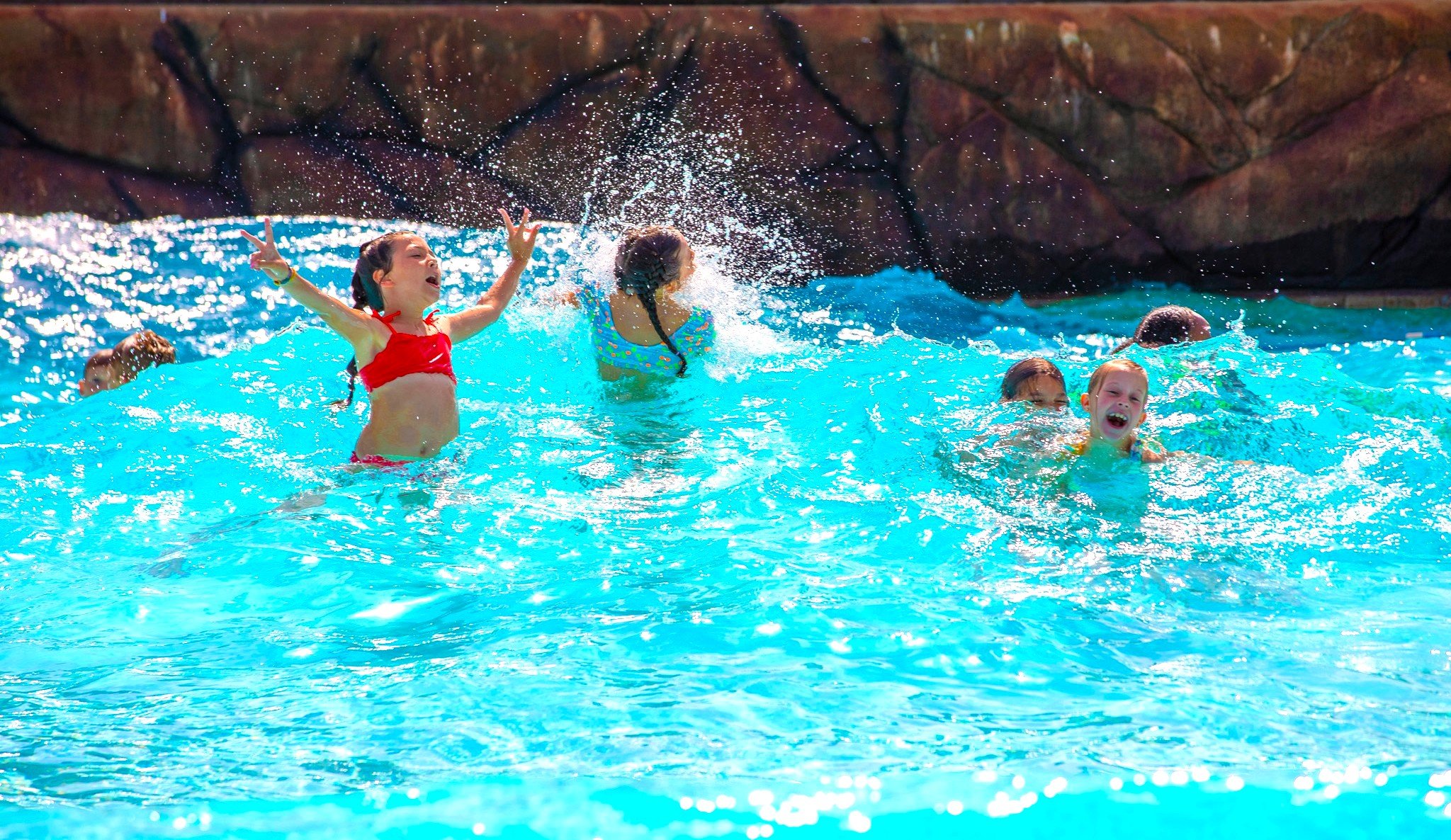 Children playing and splashing in the wave pool, enjoying summer fun.