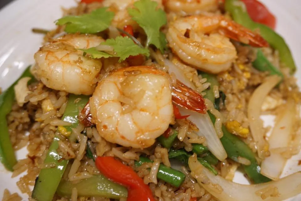Close-up of shrimp fried rice with shrimp, green and red bell peppers, onion, and cilantro.