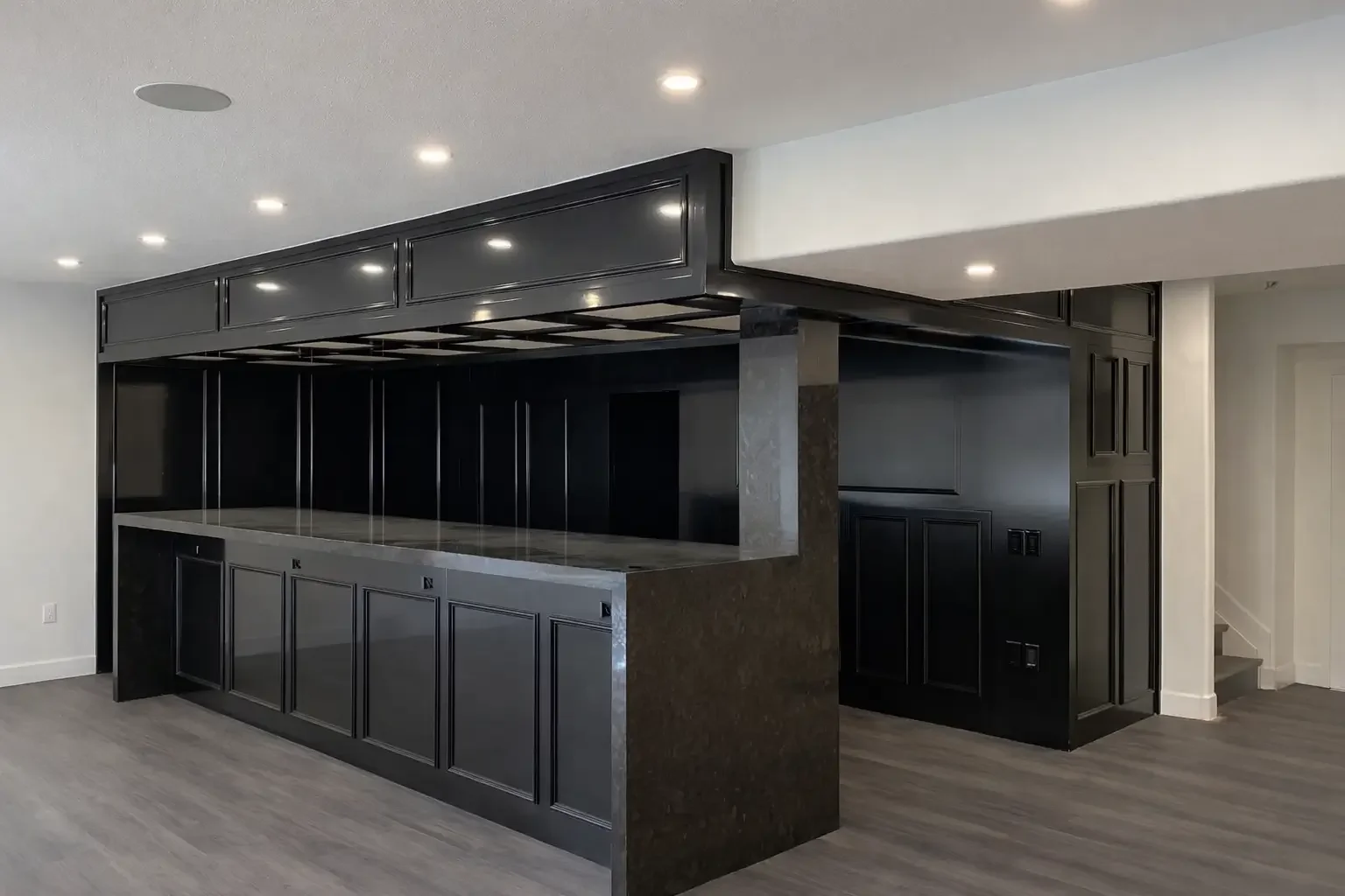 Modern kitchen island with black cabinetry and marble countertop in a minimalistic kitchen with recessed lighting.