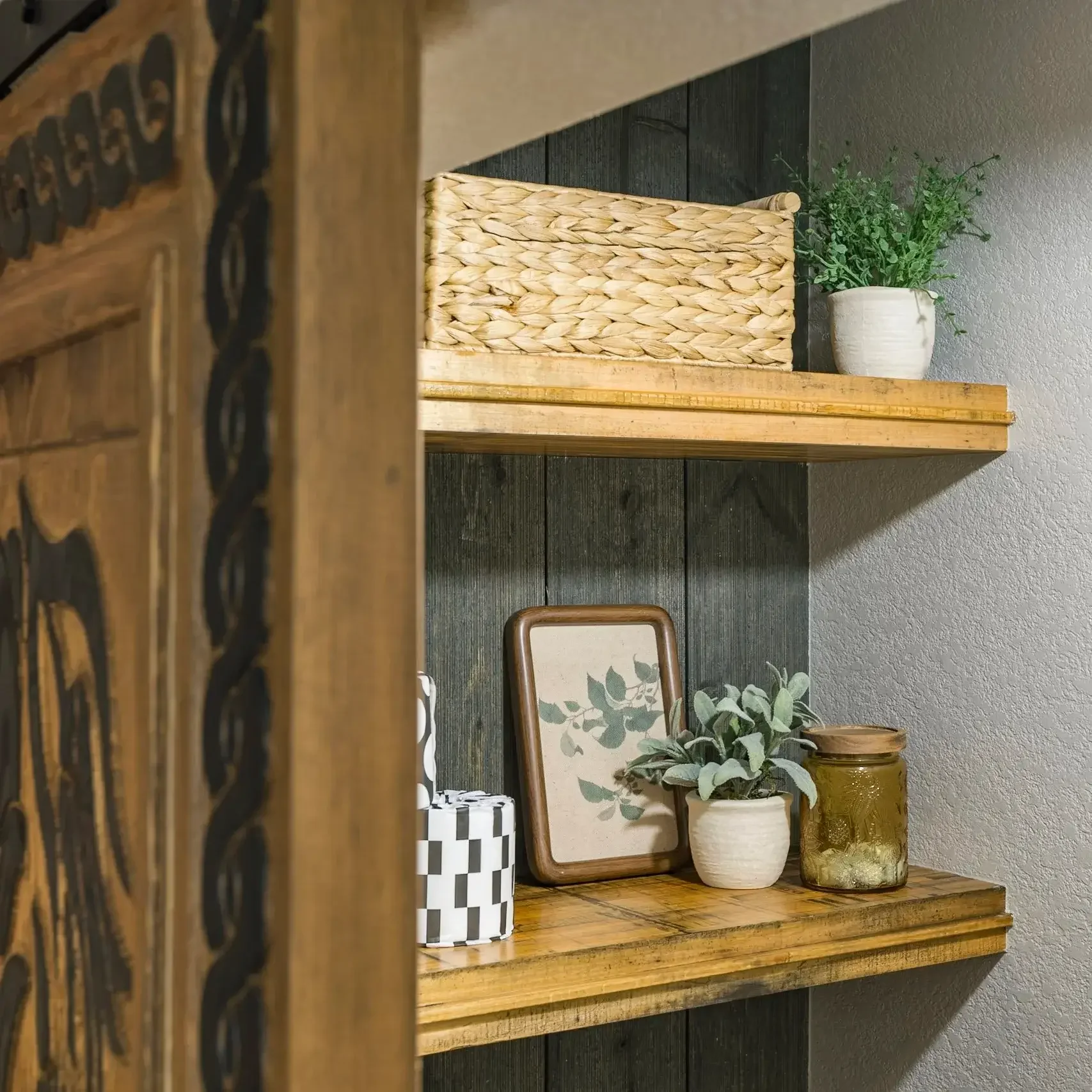 Home remodel bathroom shelving with wood shelves, woven basket, small plants, and decorative accents