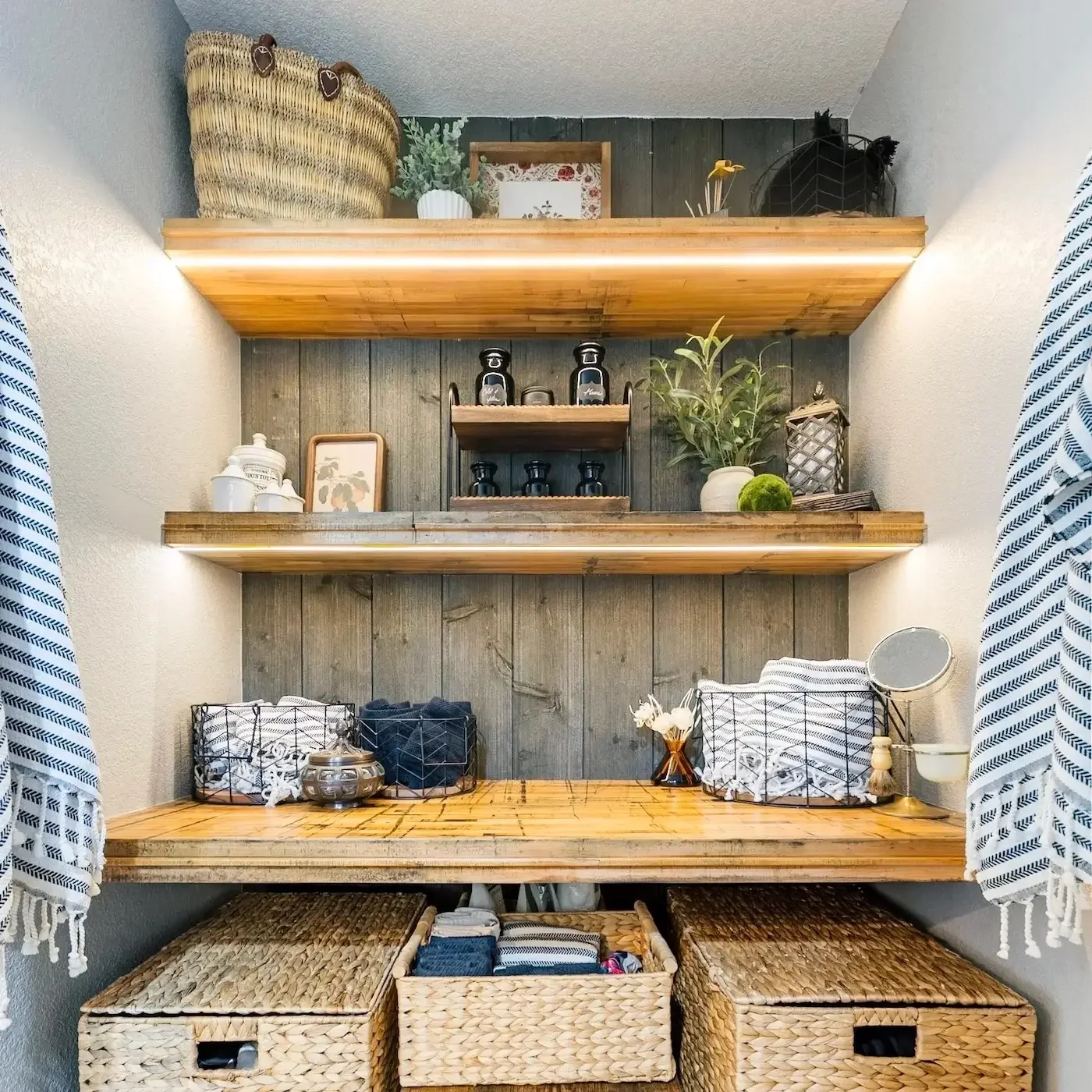 Home remodel with custom wood shelving, woven storage baskets, decorative accents, and shiplap wall backdrop