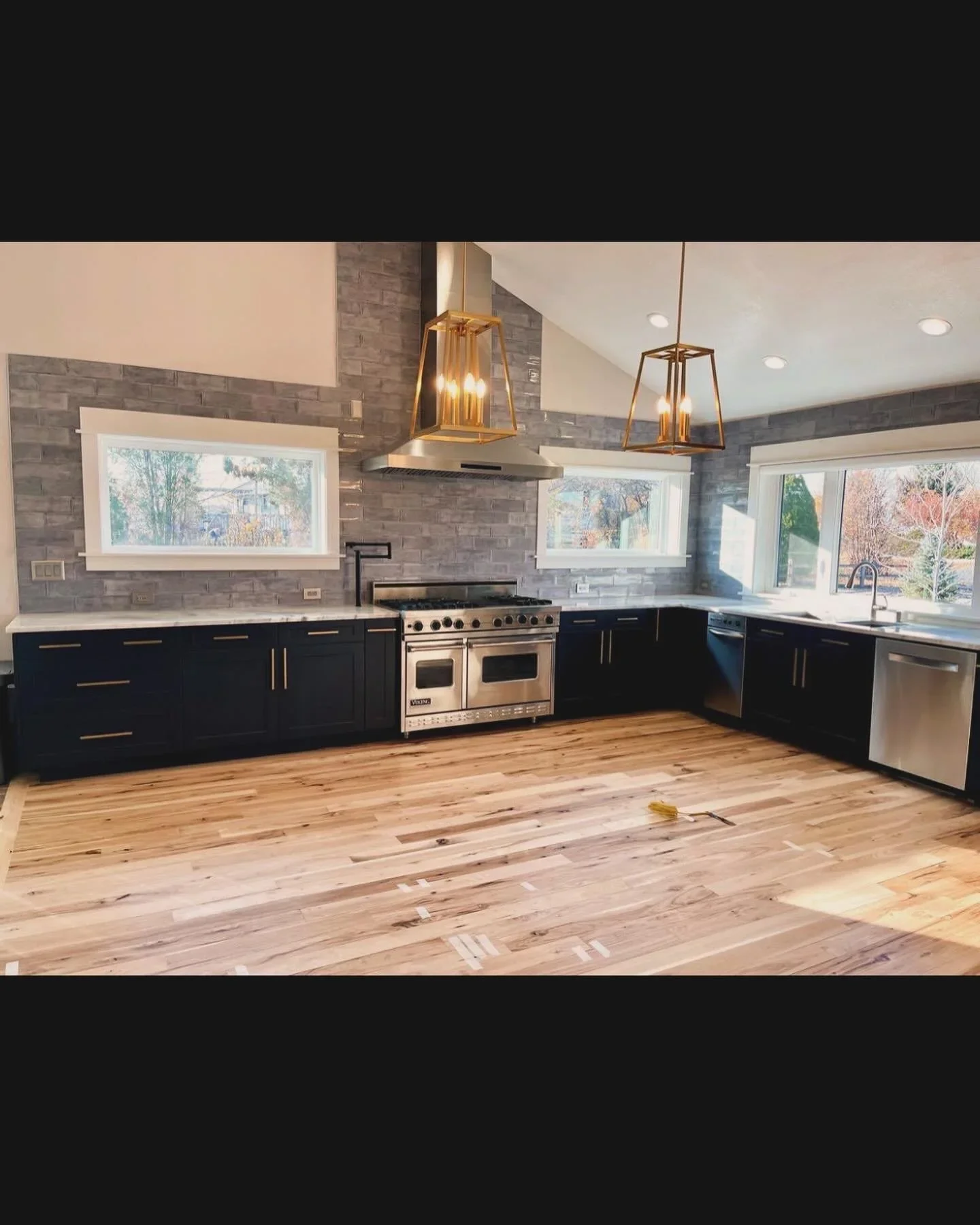 Kitchen home remodel with navy cabinets, stainless steel range, gray tile backsplash, and wood flooring