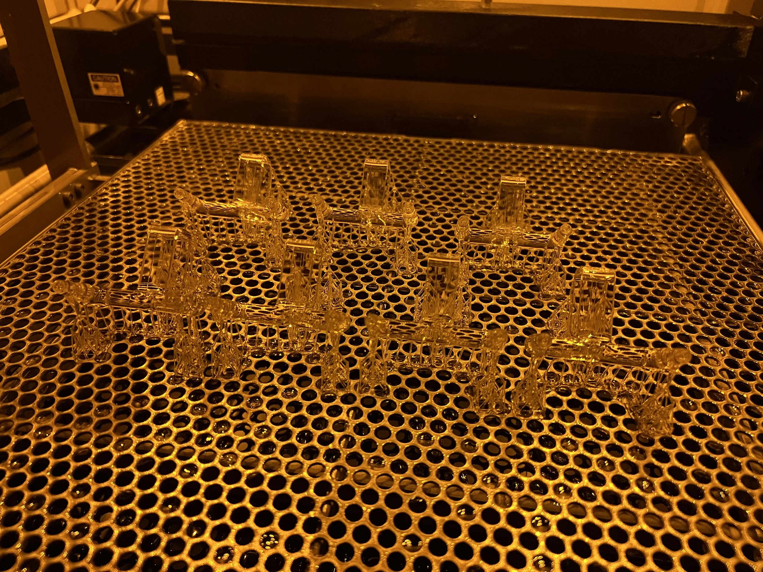 Multiple Pooetry units during SLA 3D printing, illuminated by warm orange lighting.