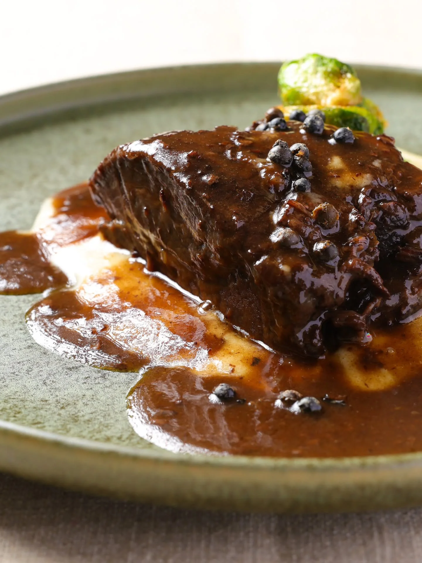 Slow-braised beef cheek, cooked low and slow until fork-tender and deeply flavorful.  Finished in a rich red wine reduction, served alongside silky aligot potatoes and crisp Brussels sprouts for balance.

This is comfort, refined.  Available during o