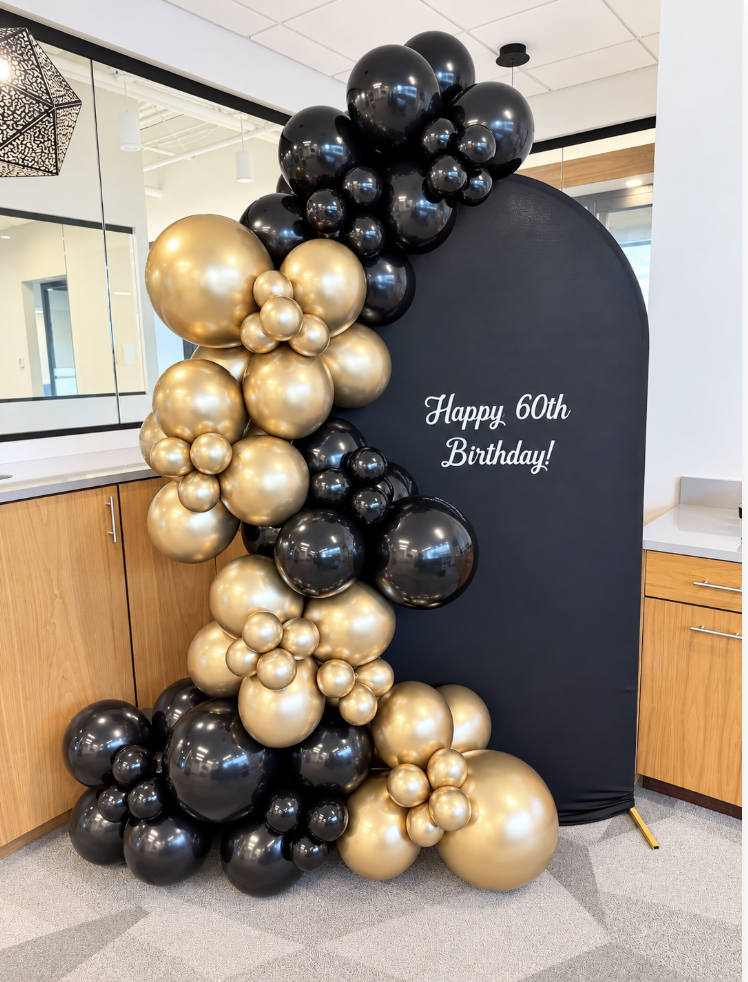 Black and gold balloon arch and backdrop with a birthday message