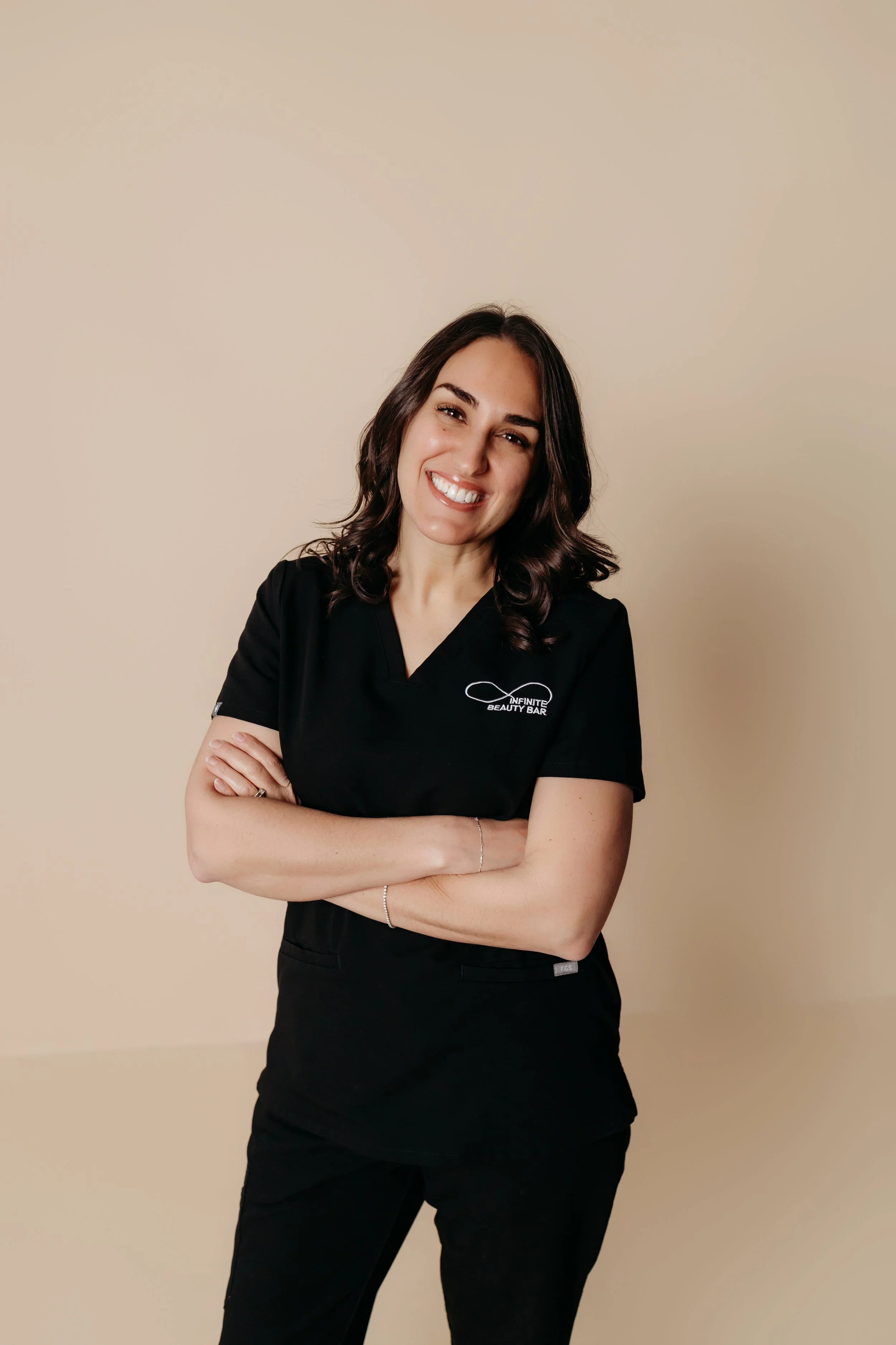 Close-up of Mik, Infinite Beauty Bar's nurse practitioner, who has dark hair and is smiling while wearing a light blue top.