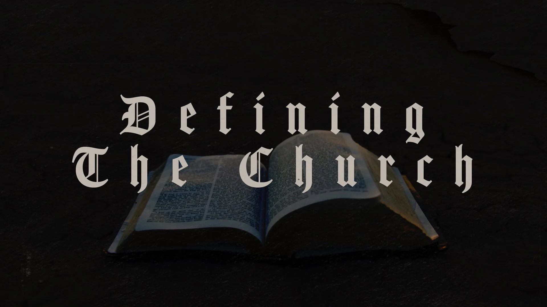 Open Bible on dark surface with overlay text 'Defining The Church' in gothic font.