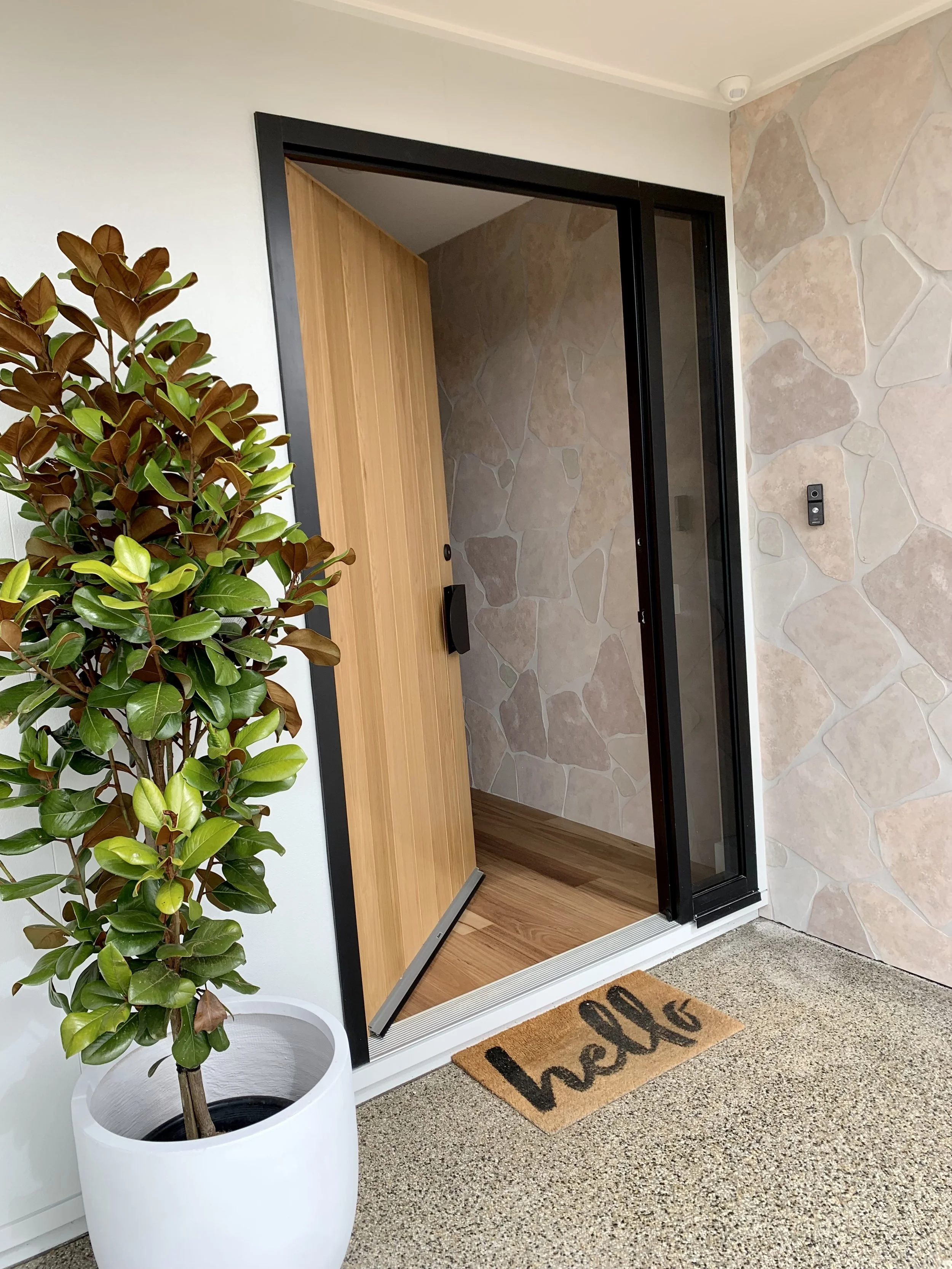 Custom Entry Door – Wangaratta. A statement American white oak entry door with a matte black handle, enhanced by crazy paving that seamlessly connects the exterior and interior.