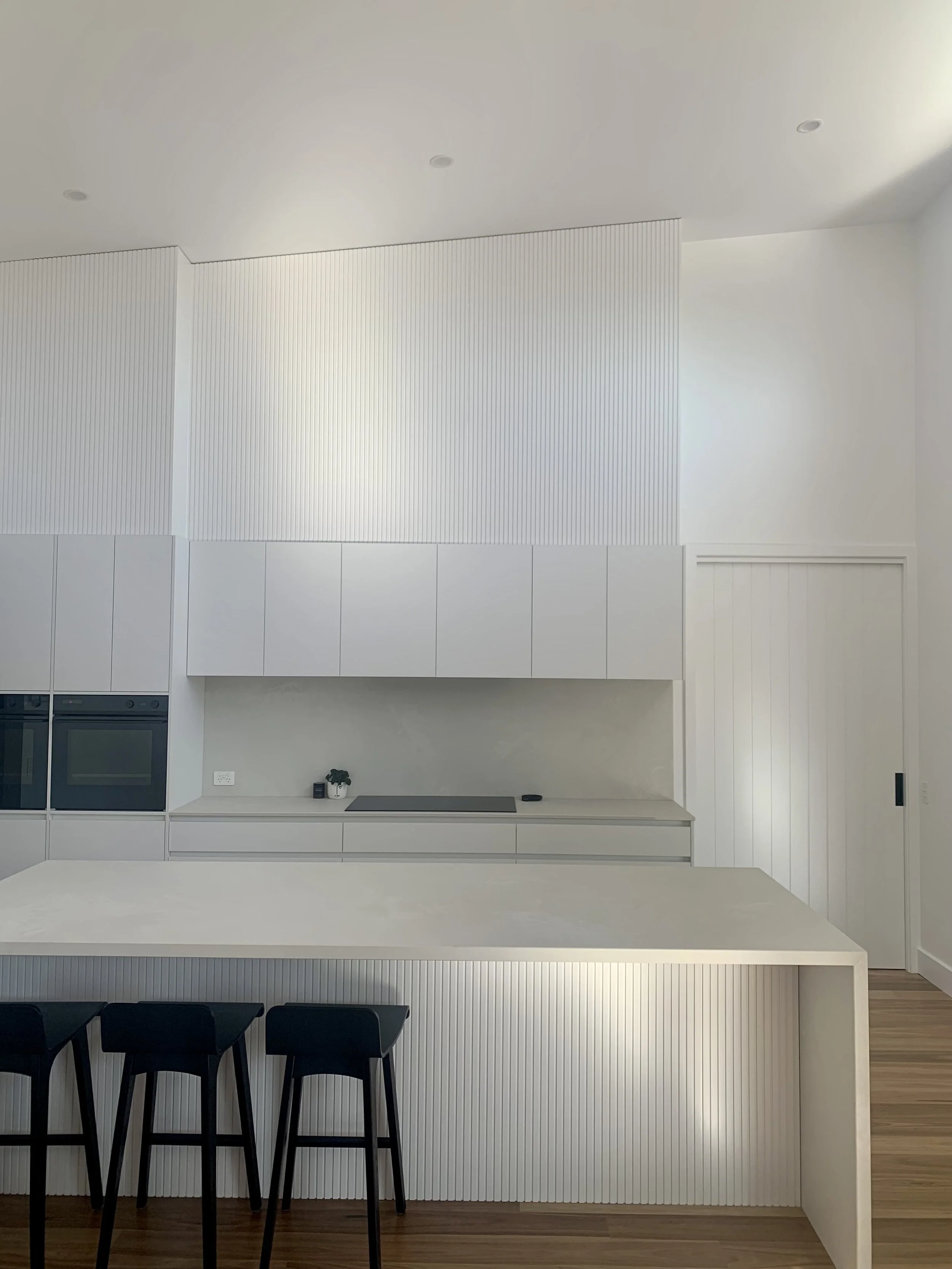 Custom Kitchen Renovation – Wangaratta. A refined open plan kitchen with Cloudburst Concrete Caesarstone benchtops and a feature lining panel, delivering a seamless blend of texture, style, and functionality.