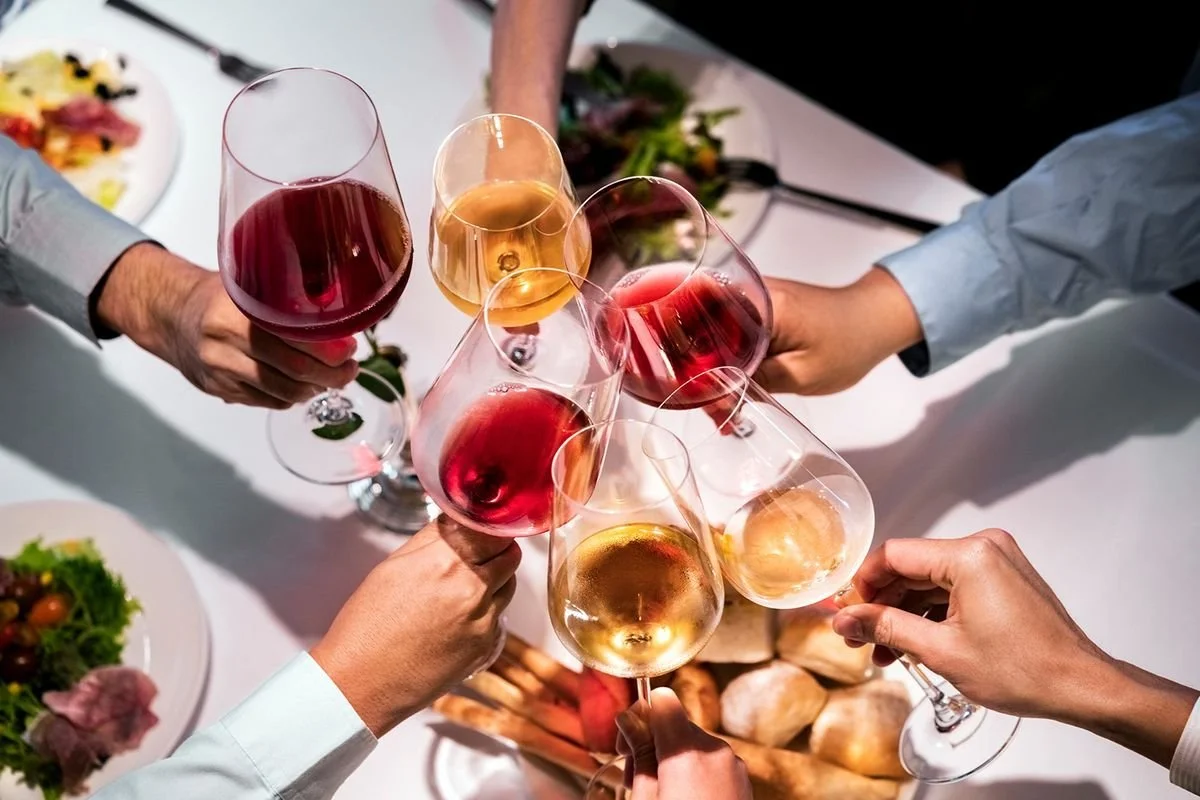 People raising glasses of wine in a toast at a celebration or dinner event.