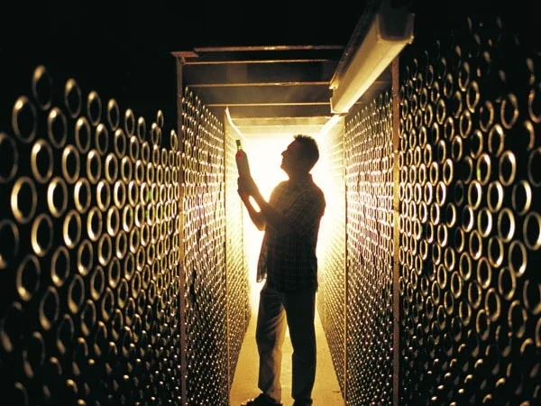 Person standing in a tunnel-like corridor with circular pattern walls, holding a spray can and illuminated by bright light from behind.