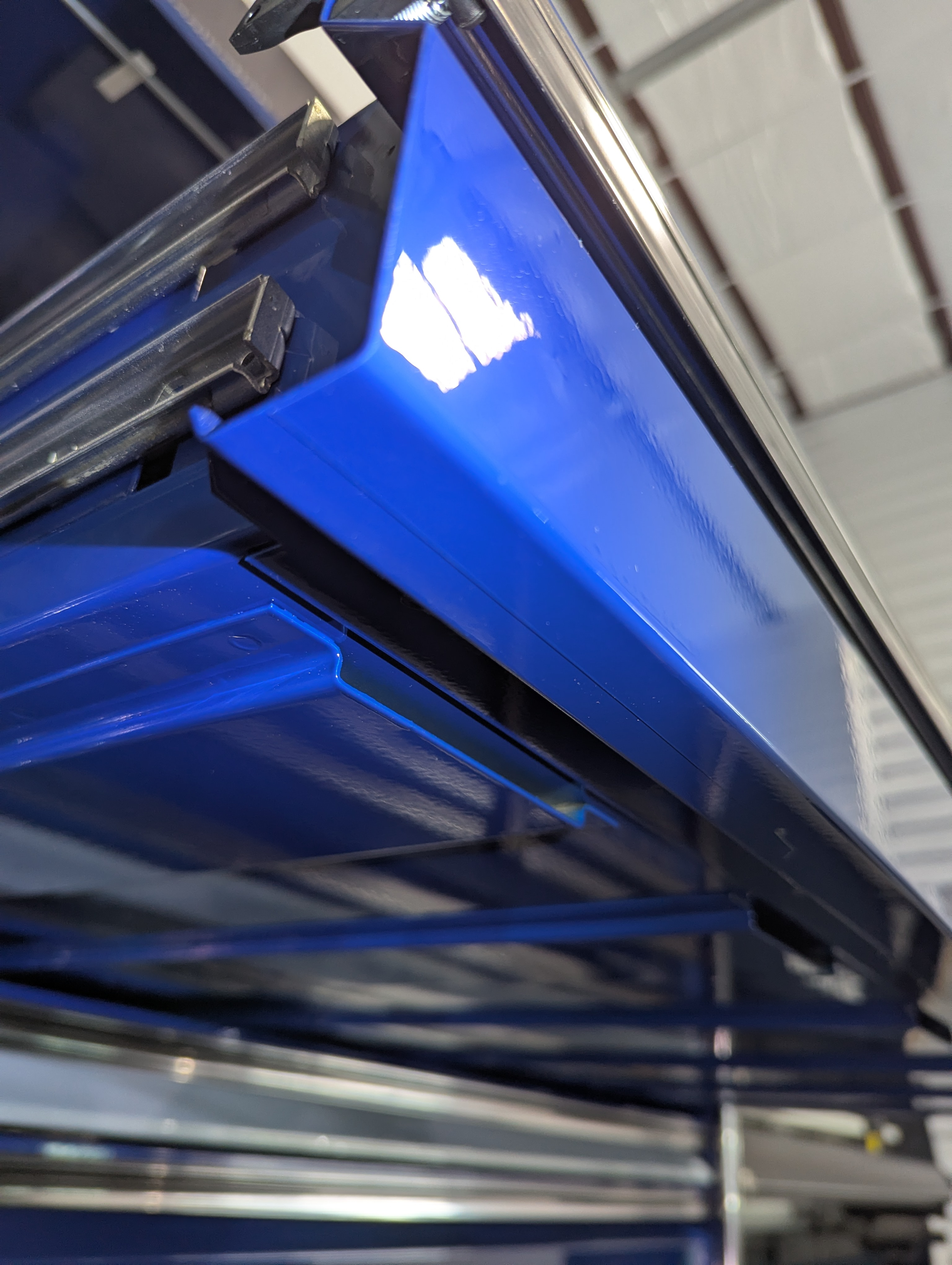 Close-up of the top edge of a blue snap-on Epiq drawer with protection film installed