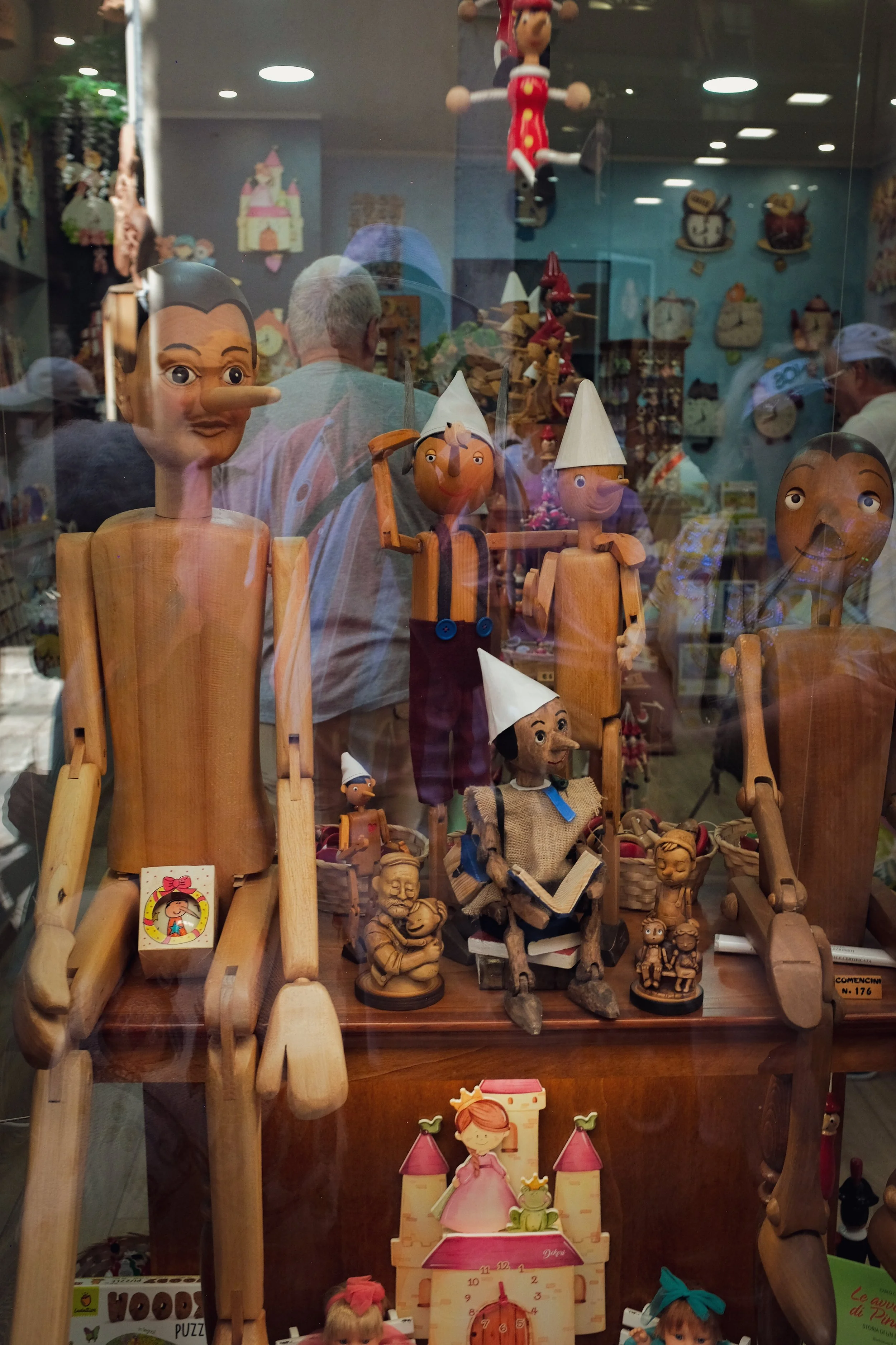 Display of wooden and painted puppets with elongated limbs and expressive faces in a toy store window.
