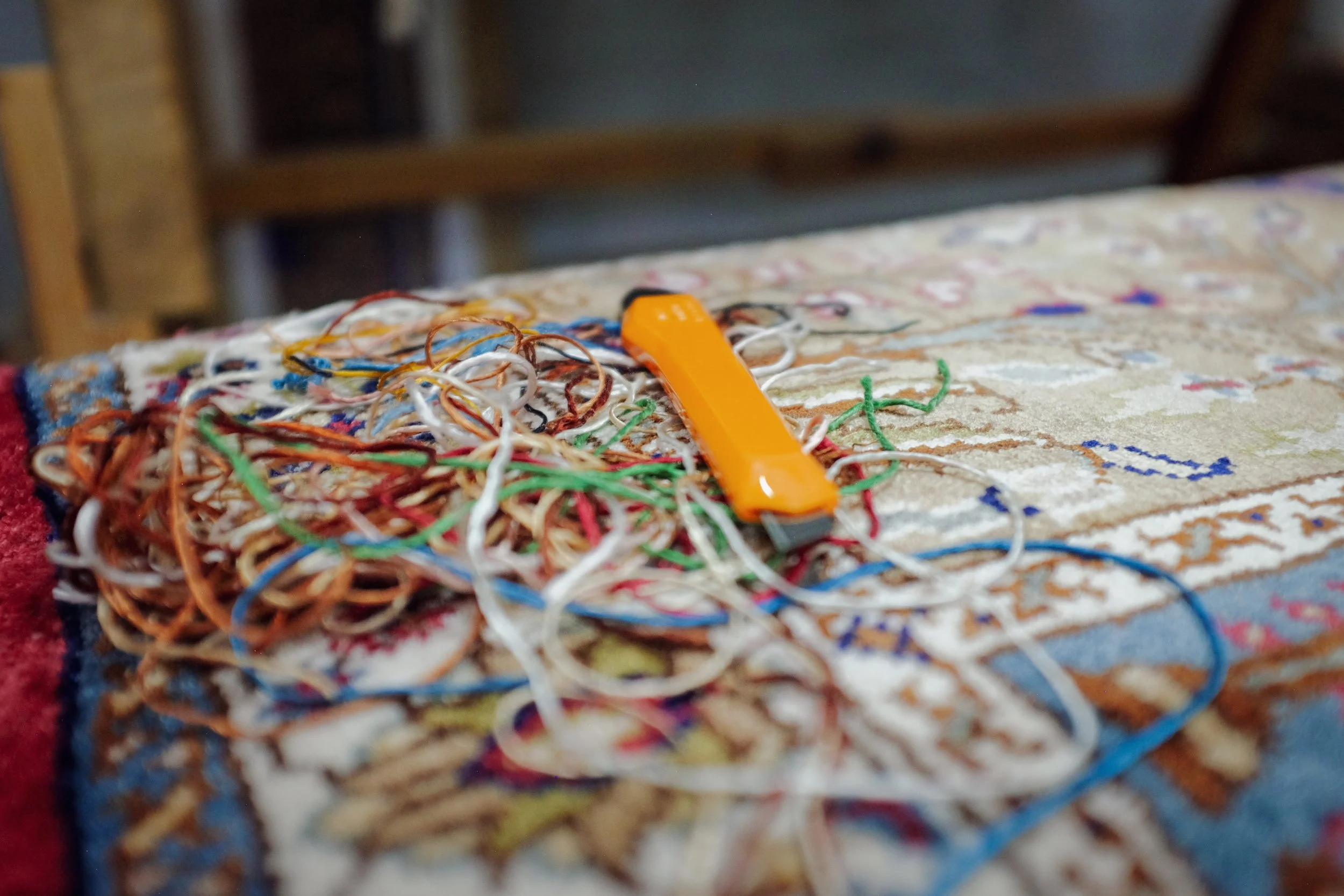 A colorful, patterned rug with a tangled pile of multicolored rubber bands and an orange device on top