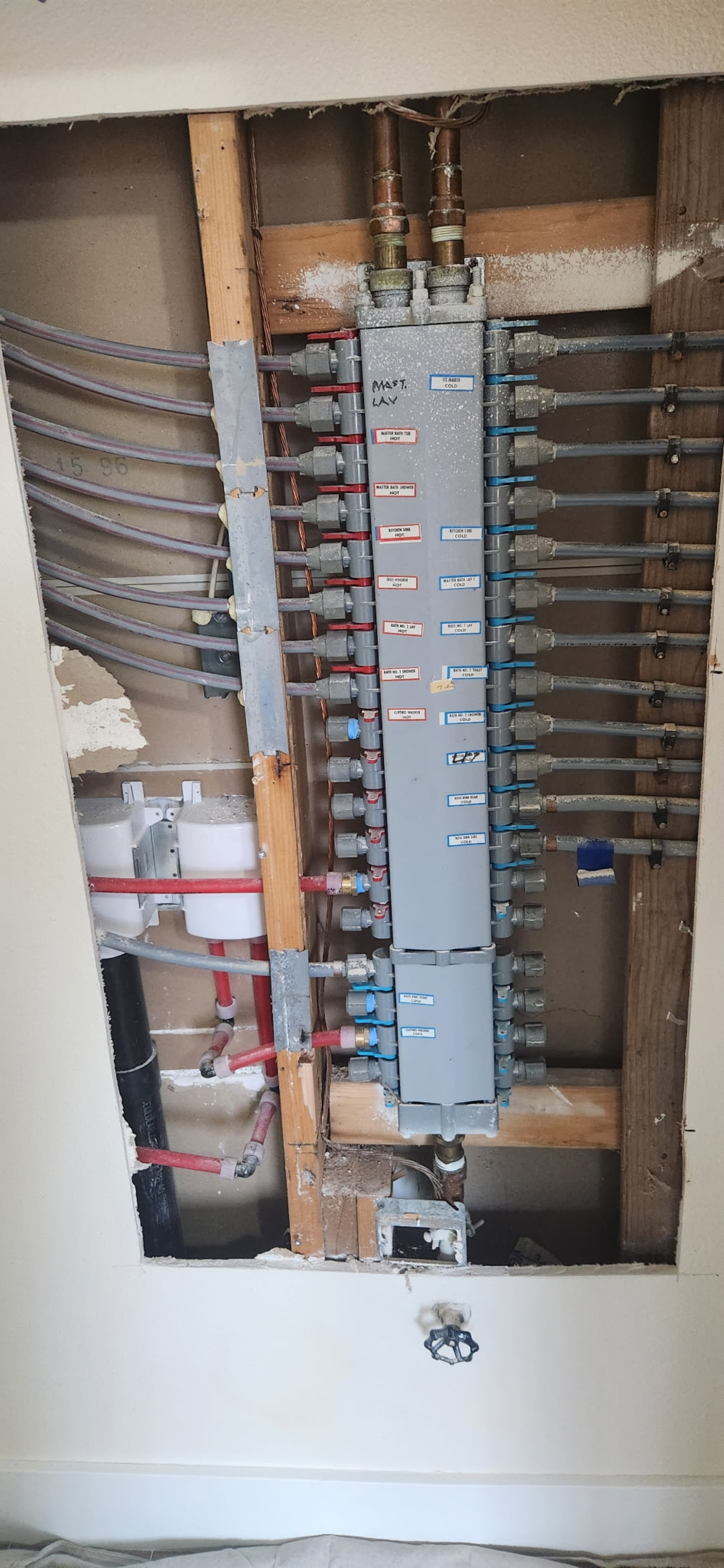 Open wall with exposed plumbing pipes and a meter panel.
