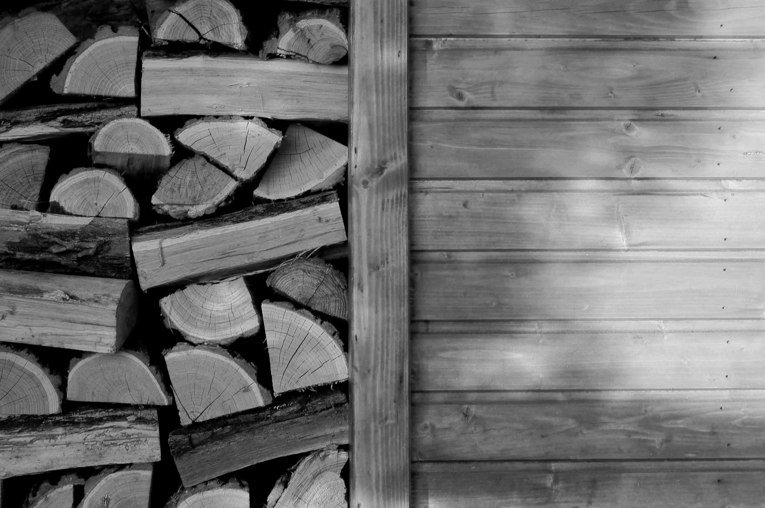 Stacked firewood on the left side and horizontal wooden planks on the right side.