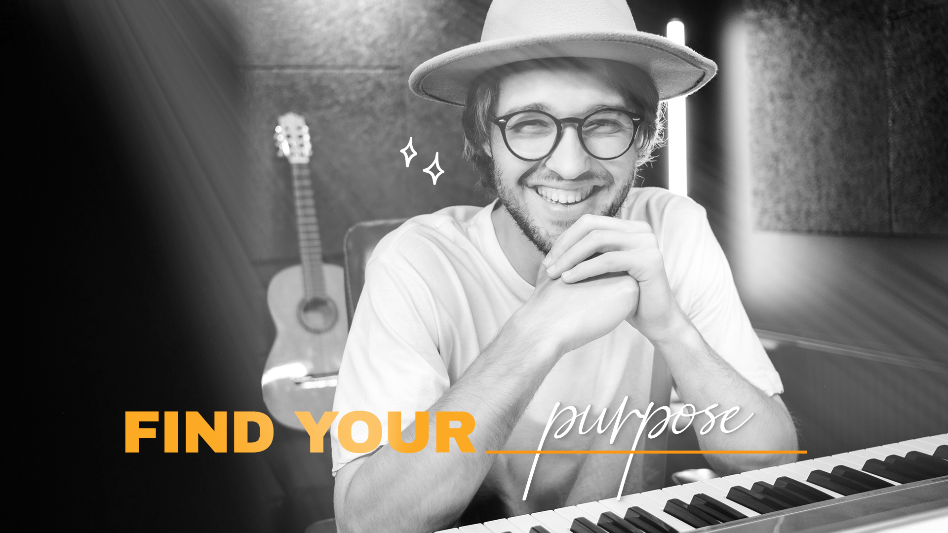 A smiling man with glasses and a hat sitting at a keyboard, with a guitar in the background, in a music studio, with the text "FIND YOUR purpose" overlayed.