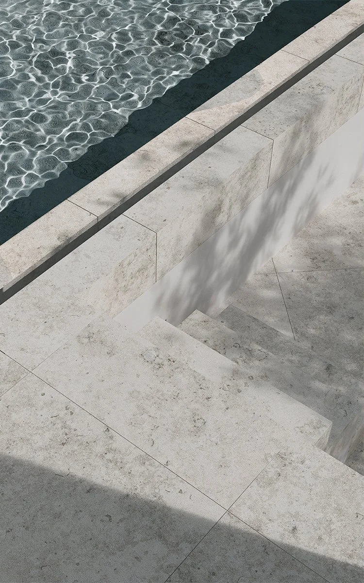 Ein moderner Wasserpool mit Wasser, das kleine Wellen verursacht, und umliegende helle Steinplatten sowie eine Treppe, die in den Pool führt.