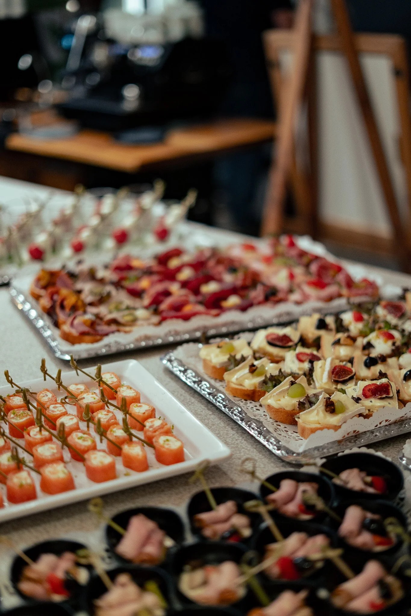 Verschiedene kalte Vorspeisen auf einem Buffet, darunter kleine belegte Brote mit Käse, Wurst und Obst, sowie kleine marinierte Fisch- und Fleischhäppchen.