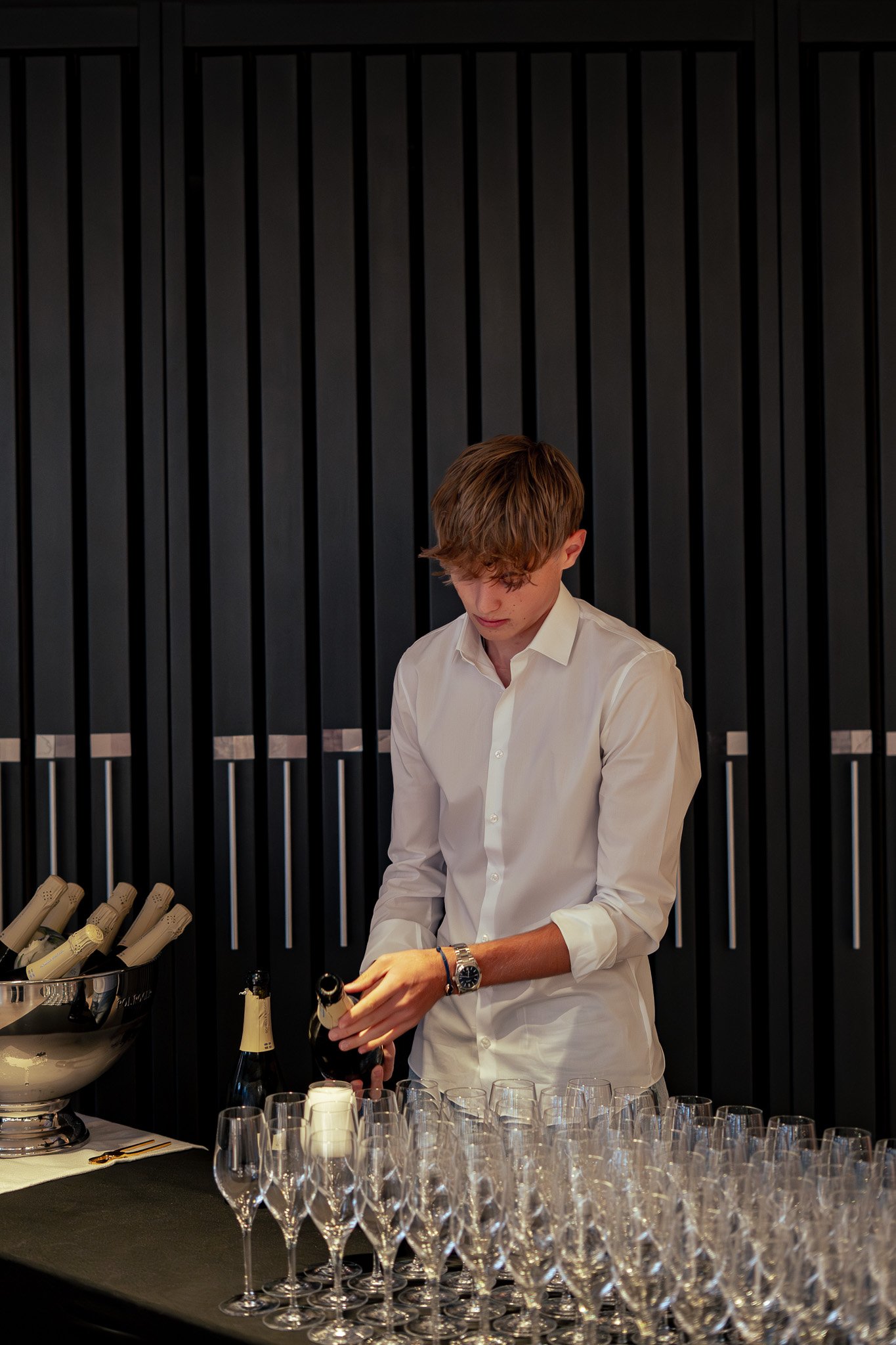 Junge man in weißem Hemd schenkt Champagner in Gläser in einer eleganten Bar