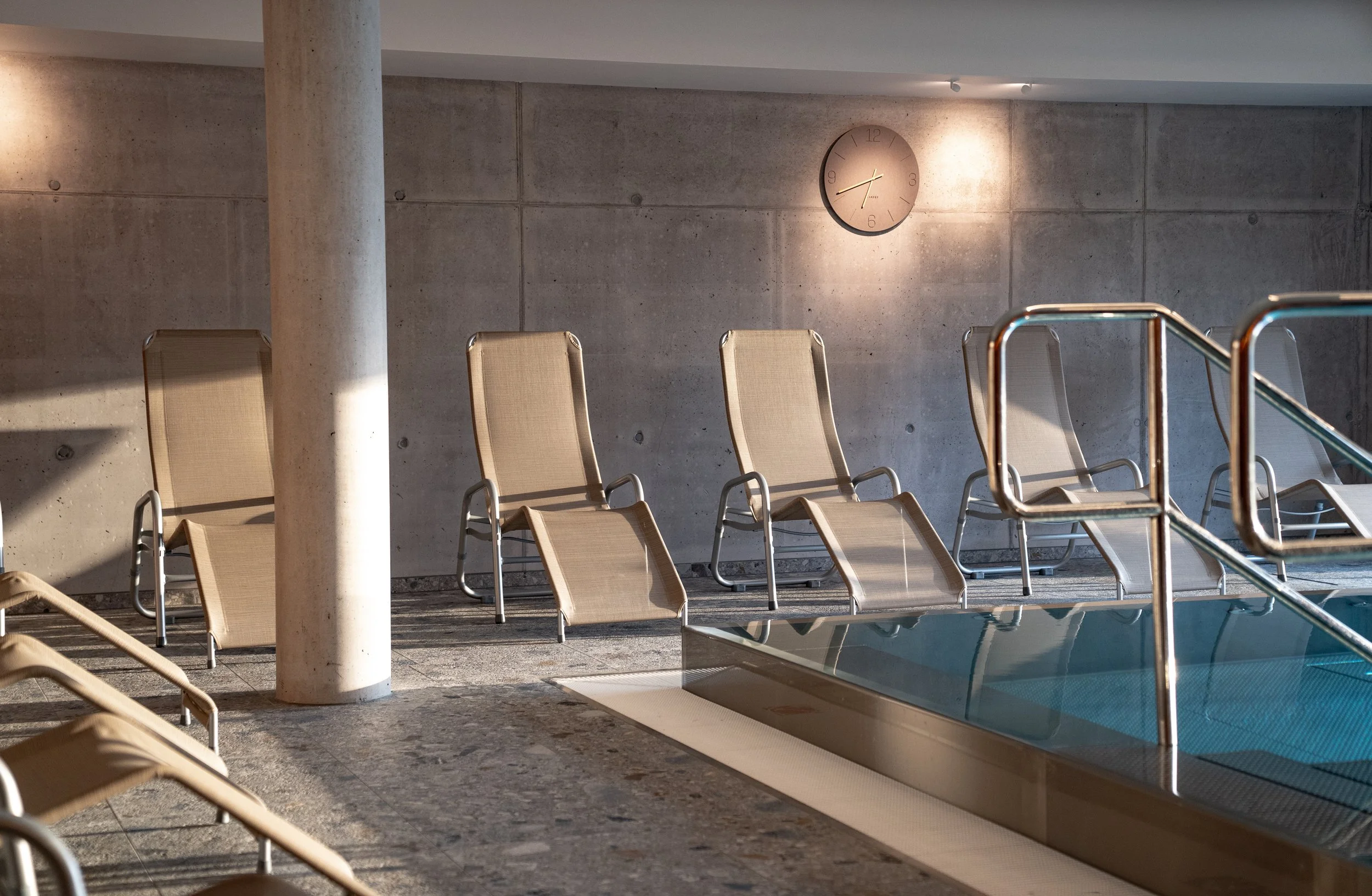 Leere Liegen am Schwimmbecken in einem modern gestalteten Schwimmbad.