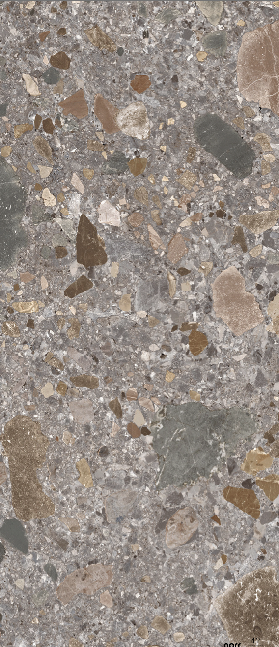 Nahaufnahme einer Beton- oder Steinfläche mit verschiedenen kleinen Steinen in unterschiedlichen Farben und Formen.