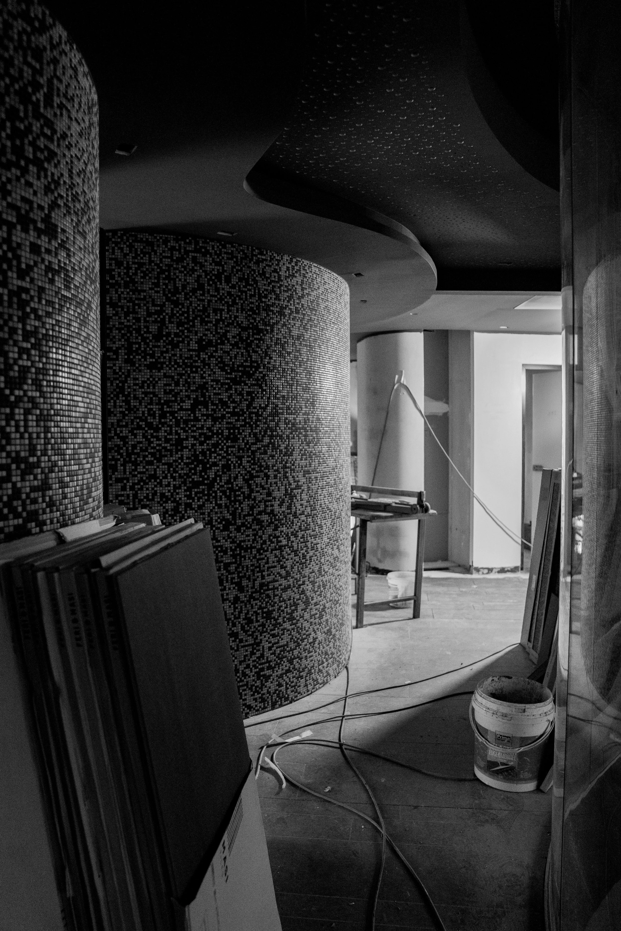 Innenaufnahme einer Baustelle mit Rollläden, Werkzeugen, Kabeln und Baumaterialien, vermutlich in einem Gebäude im Bau oder Umbau.