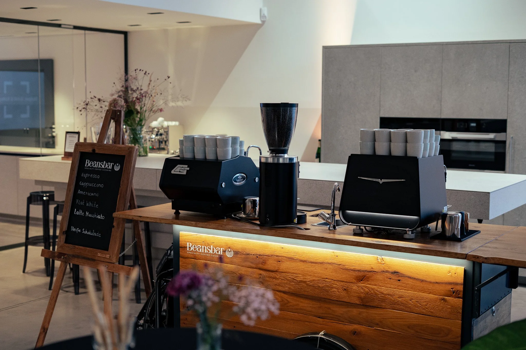 Moderne Kaffeezubereitung in einem Café mit Holzbar, Kaffeemaschinen, Kaffeetassen und einem kleinen schwarzenboard