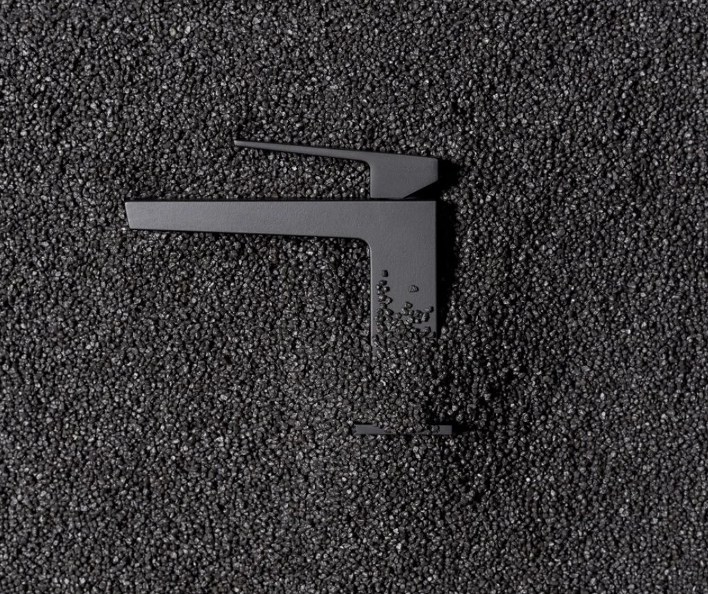 Schwarze Kunststoffteile auf schwarzem Kieseluntergrund, vermutlich ein abgebildeter Werkzeug- oder Bauteil.