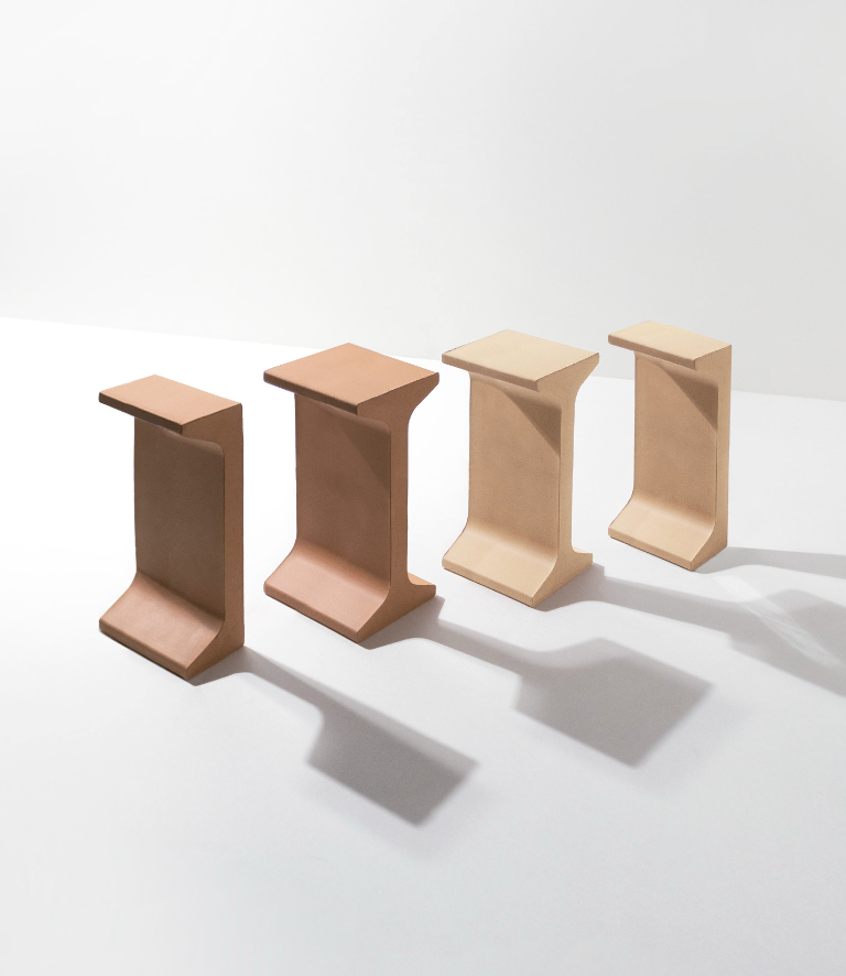 Vier minimalistisches, beige und terrakottafarbene Möbelstücke mit geschwungenen Formen, die Schatten auf einem weißen Hintergrund werfen.