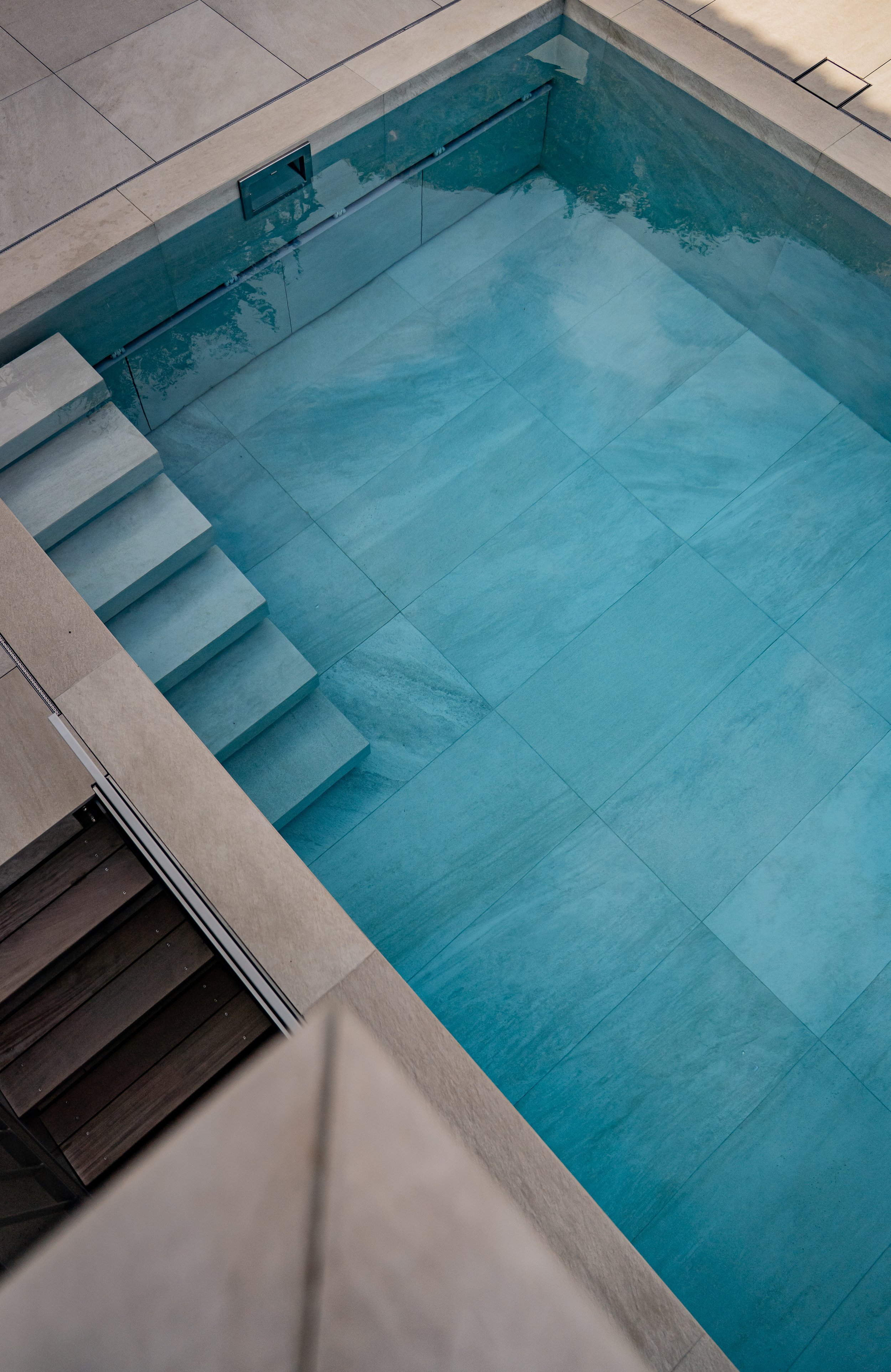 Leeres, neues Schwimmbecken mit blauen Fliesen, seitliche Stufen, in einem modernen Schwimmbad.
