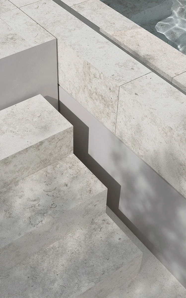 Nahaufnahme von Treppen aus hellem Stein mit Schatten und Wasser im Hintergrund.