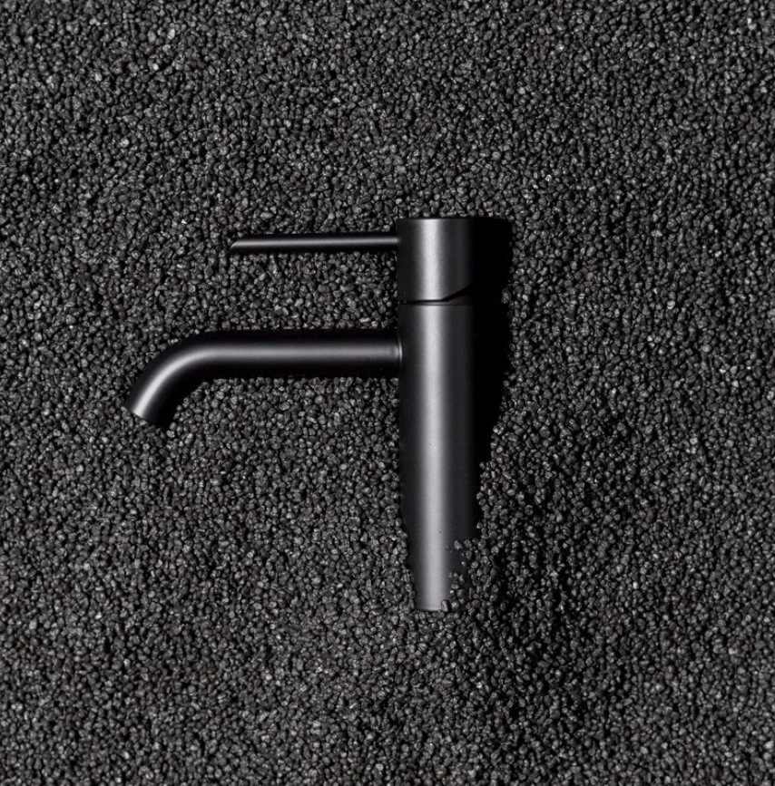 Schwarzer Wasserhahn auf schwarzem, strukturierter Hintergrund.