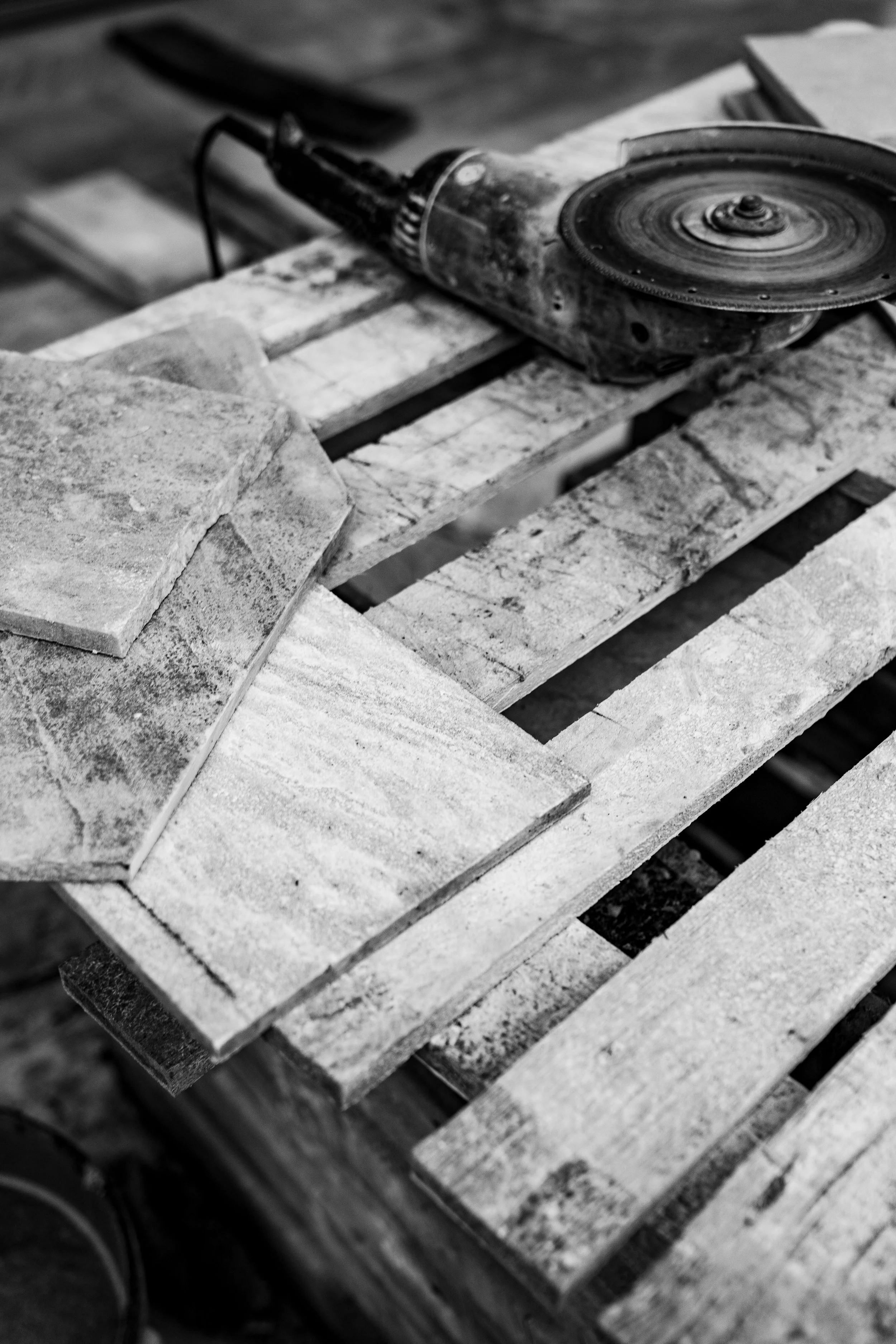 Ein Elektroschleifer liegt auf einem Holzgestell aus Paletten.