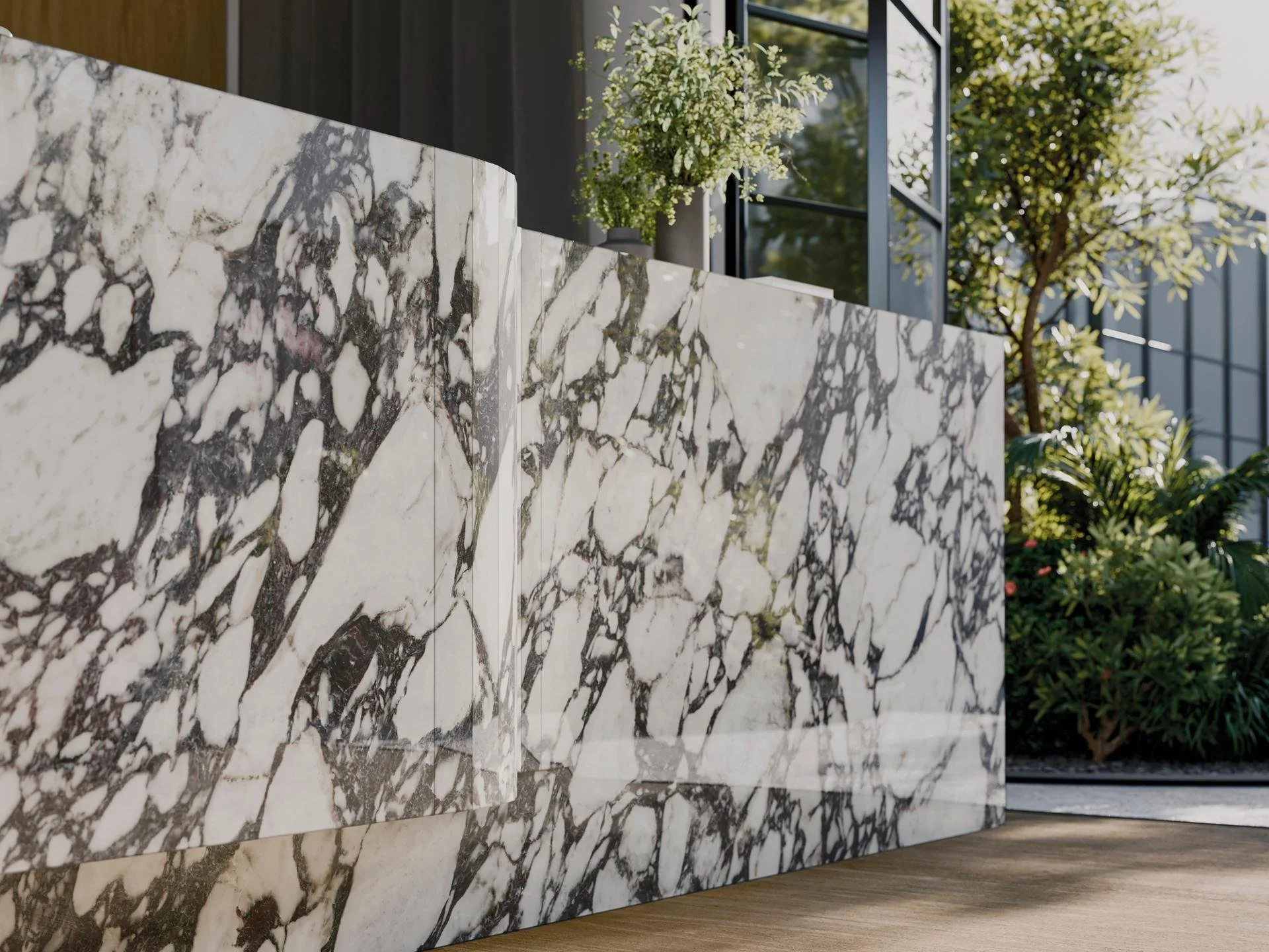 Innenansicht mit einer Theke aus schwarzem und weißem Marmor, im Hintergrund große Glastüren und grüne Pflanzen.