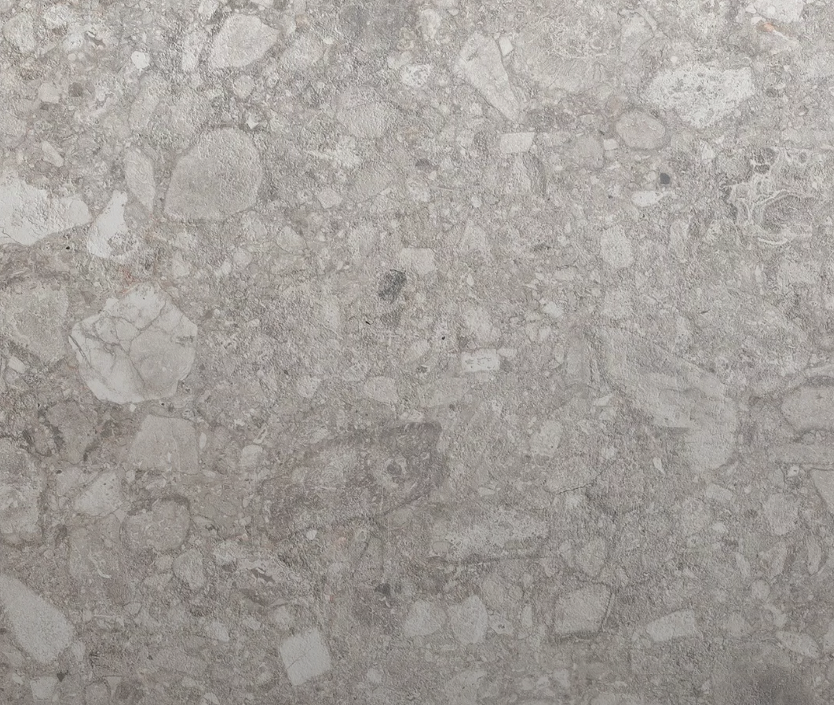 Nahaufnahme einer Betonoberfläche mit sichtbaren Kieselsteinen und Steinen