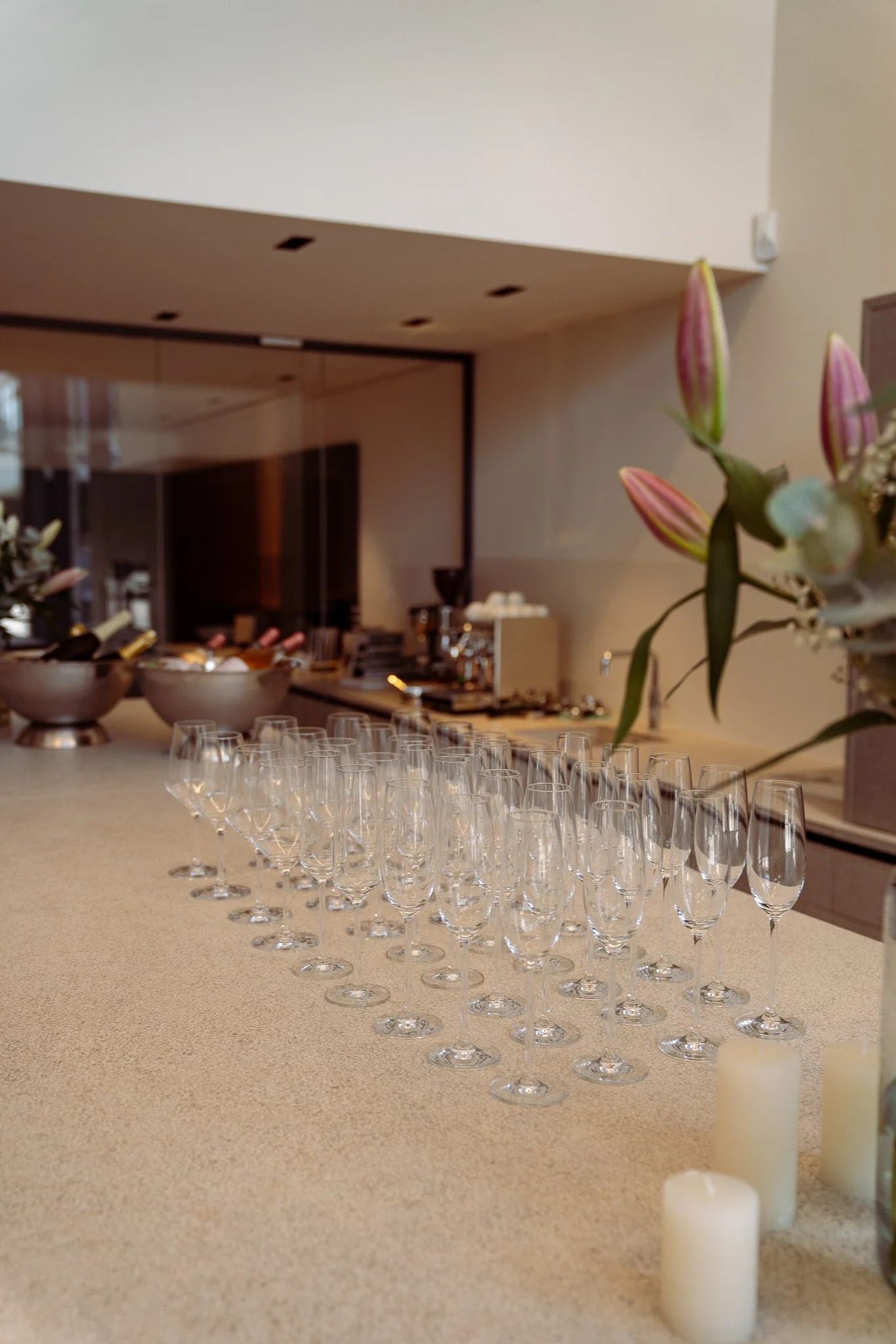 Mehrere leere Champagnergläser auf einer Theke mit Blumen und Dekoration im Hintergrund.