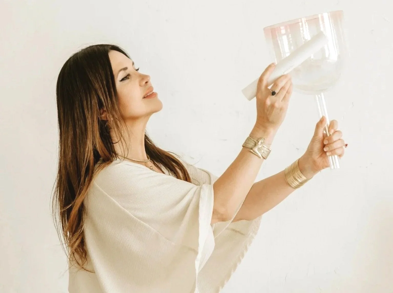 A woman with long brown hair holding a large empty wine glass while cleaning it with a white cloth.