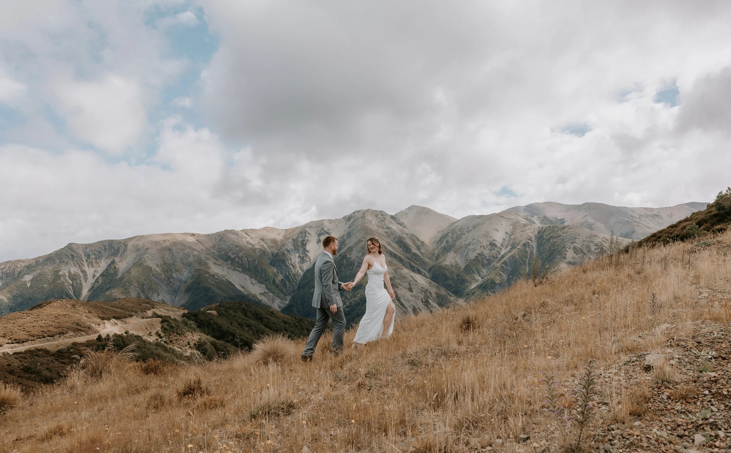 bride leads groom up the hill smiling