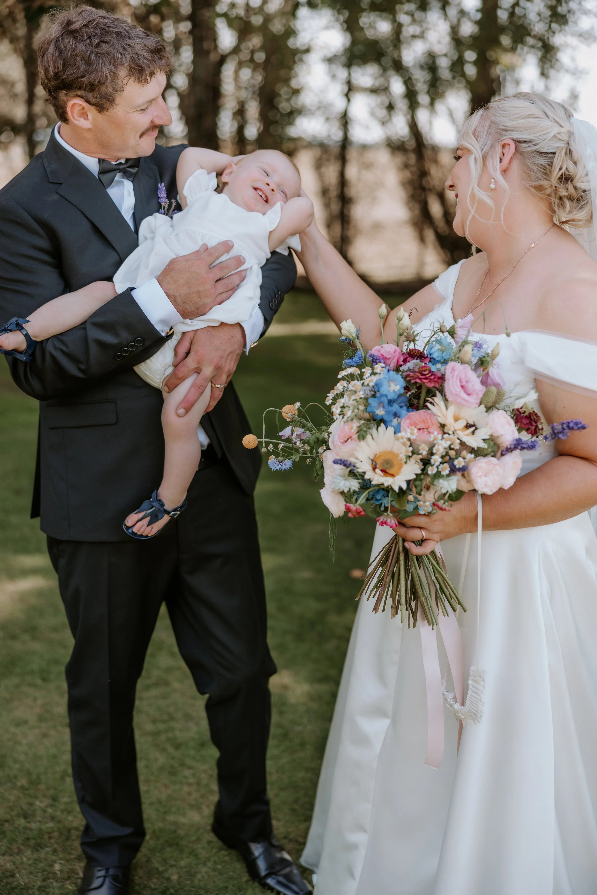 bride and groom playing with their child
