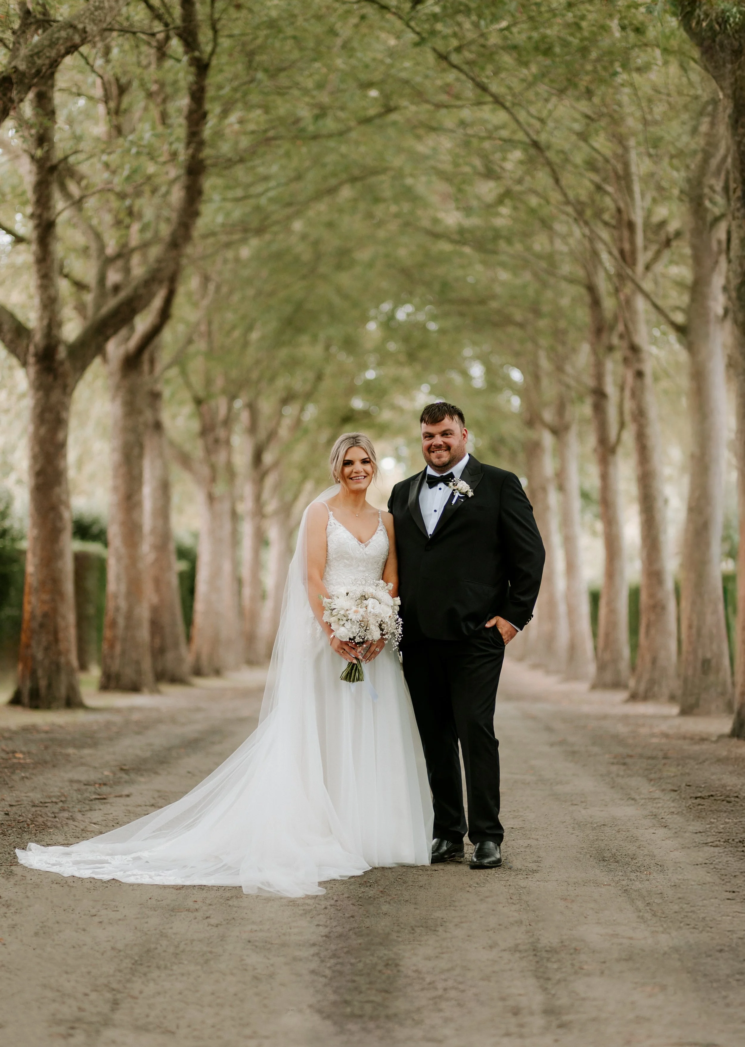 bride and groom standing in green driveway