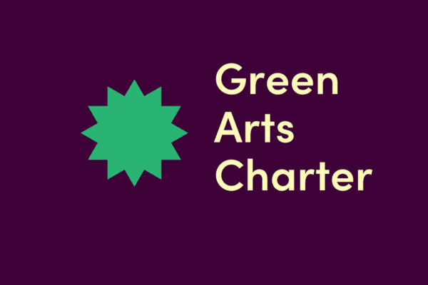 Green Arts Charter logo with green starburst symbol and beige text on a dark purple background.