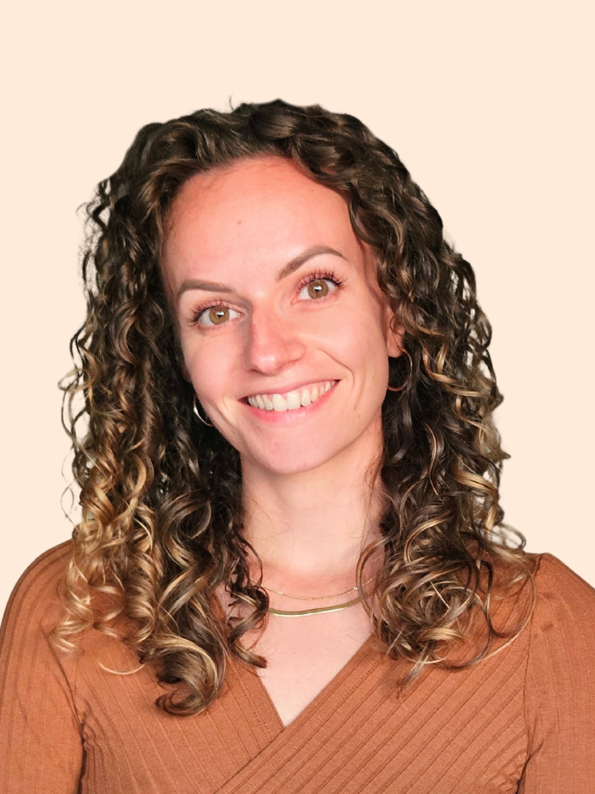 Une femme souriante avec des cheveux bouclés, portant un haut marron et un collier doré.