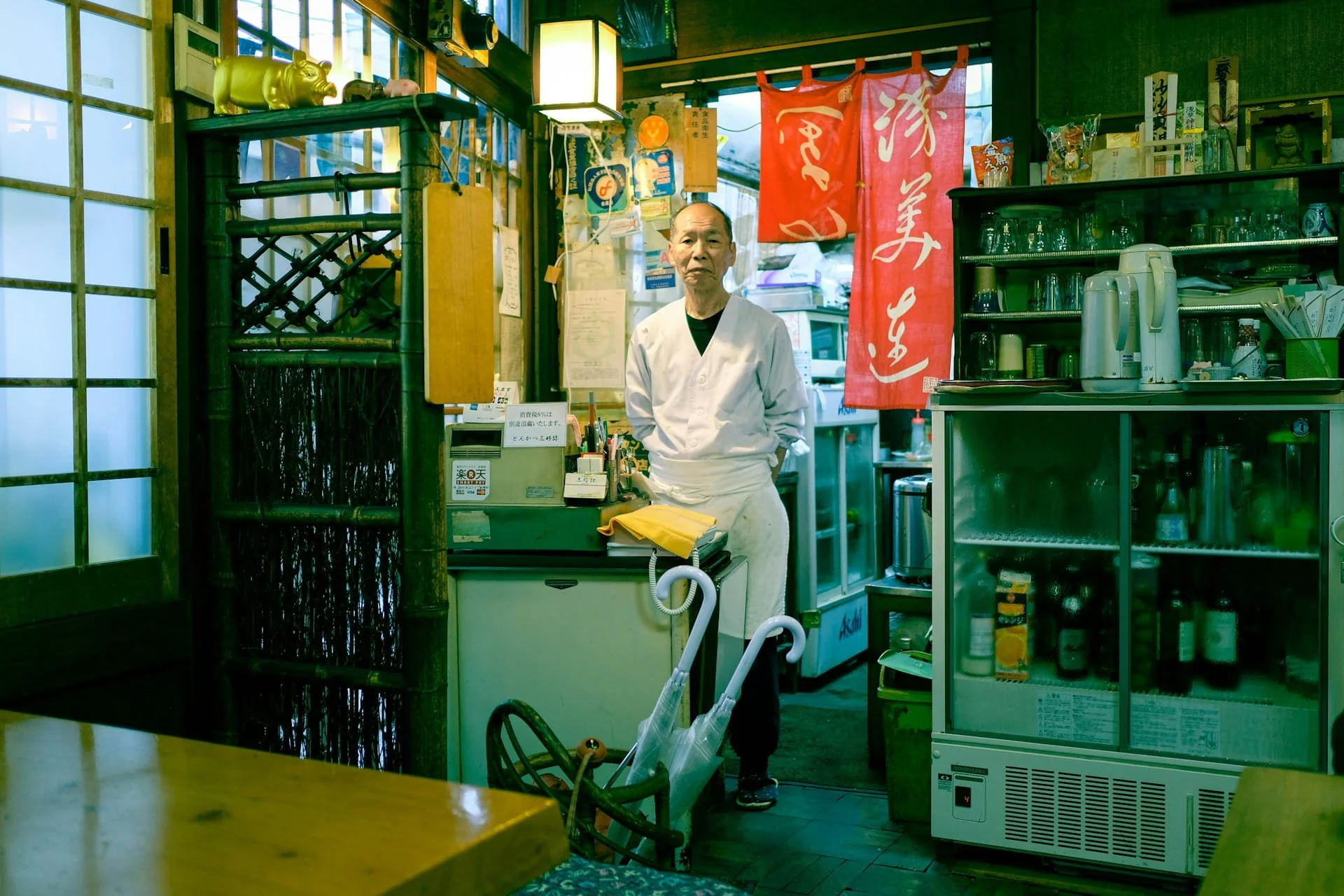 Japanese restaurant owner standing behind the counter of a traditional old shokudo, Japan
