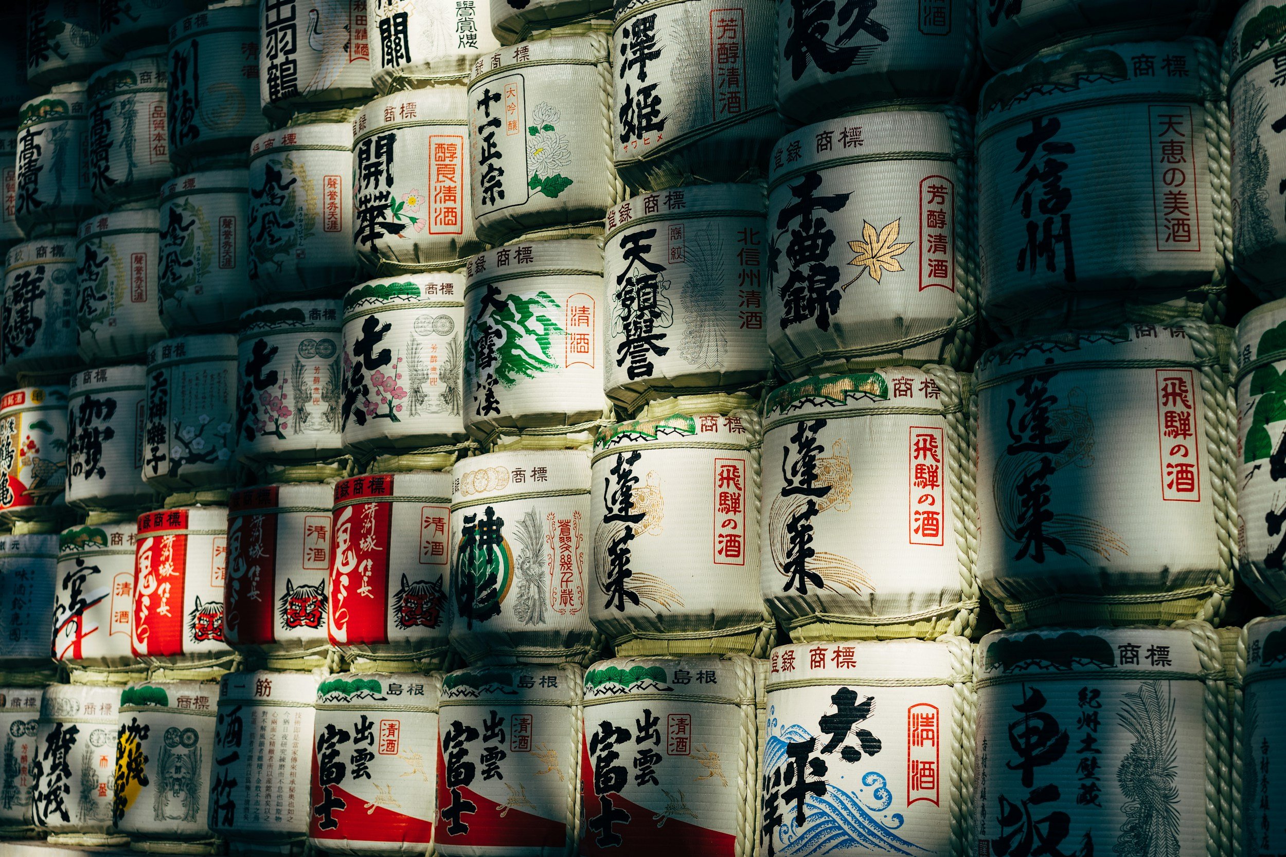 Stacked traditional Japanese sake barrels with colorful labels and Japanese characters.