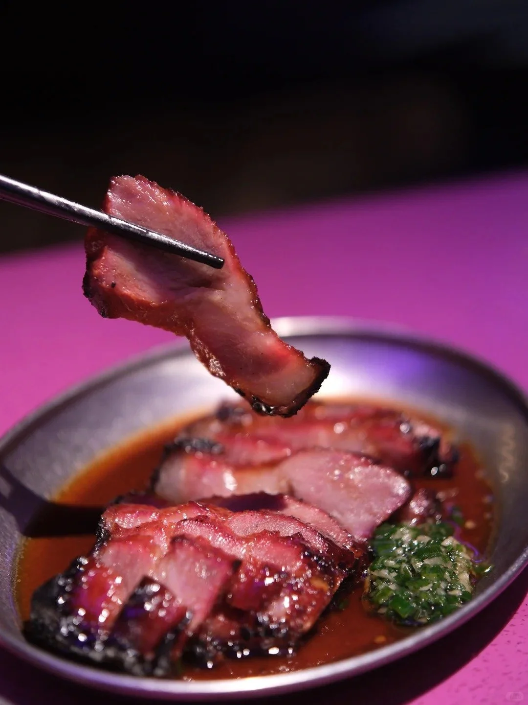 Someone using chopsticks to pick up a piece of char siew pork at Bastard in Shanghai