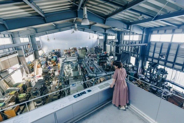 Visitor looking down from the observation deck at the workshop floor of Takefu Knife Village, Echizen