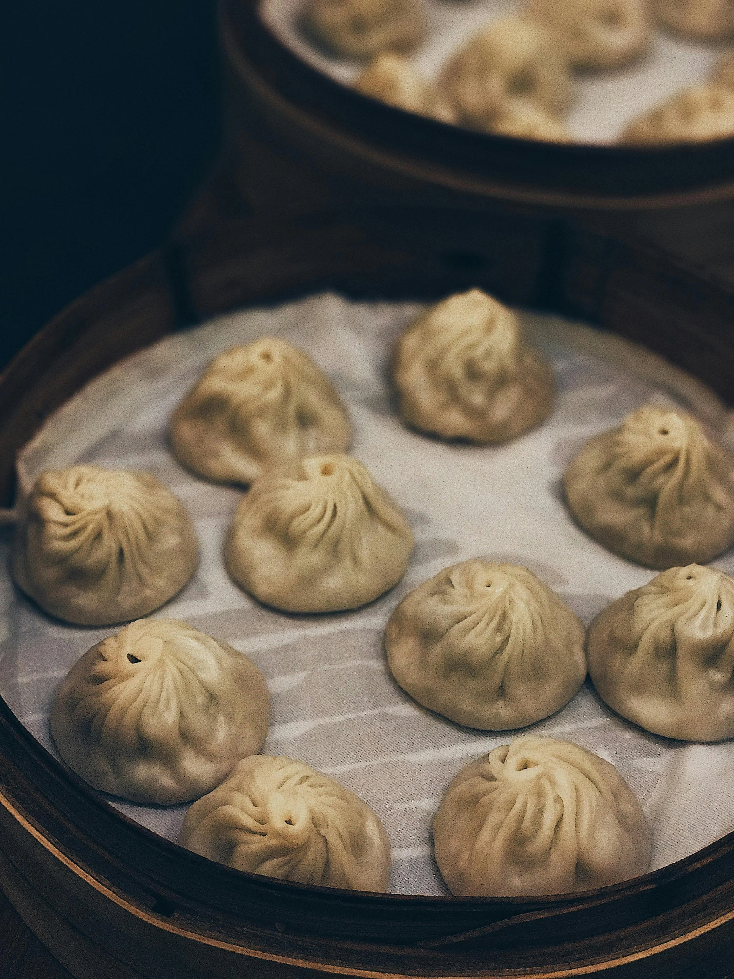 Steamed xiaolongbao soup dumplings inside a bamboo steamer lined with parchment paper.
