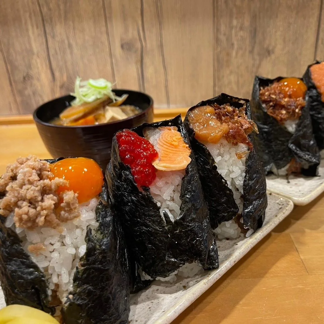 Gourmet, handmade onigiri in a row on a plate, with various ingredients on top